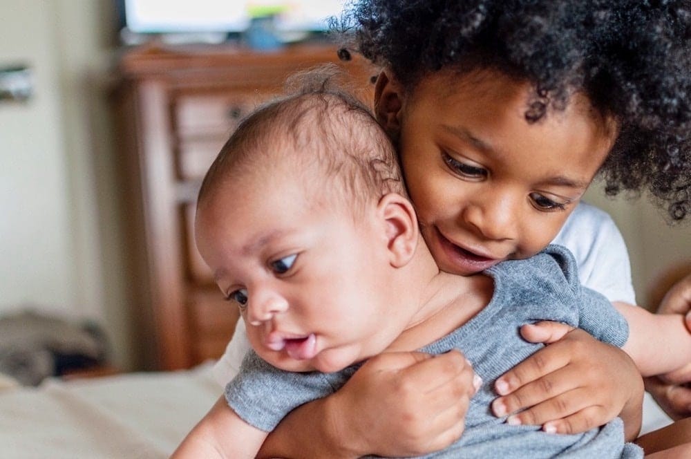 older sibling holding baby