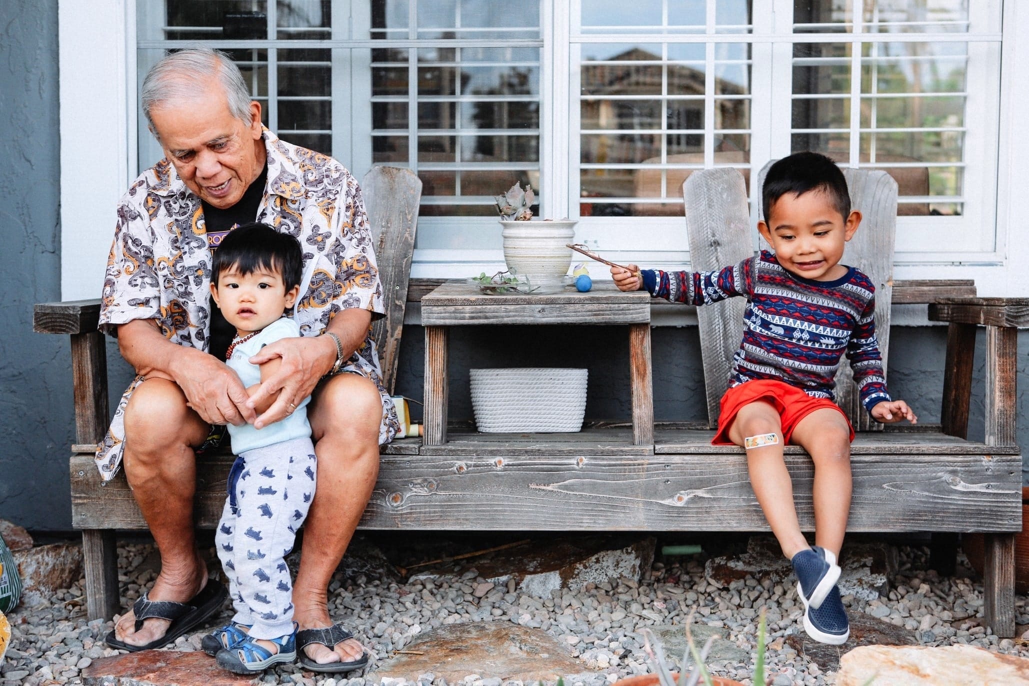 grandpa playing with grandkids on a porch- grandparents babysitting