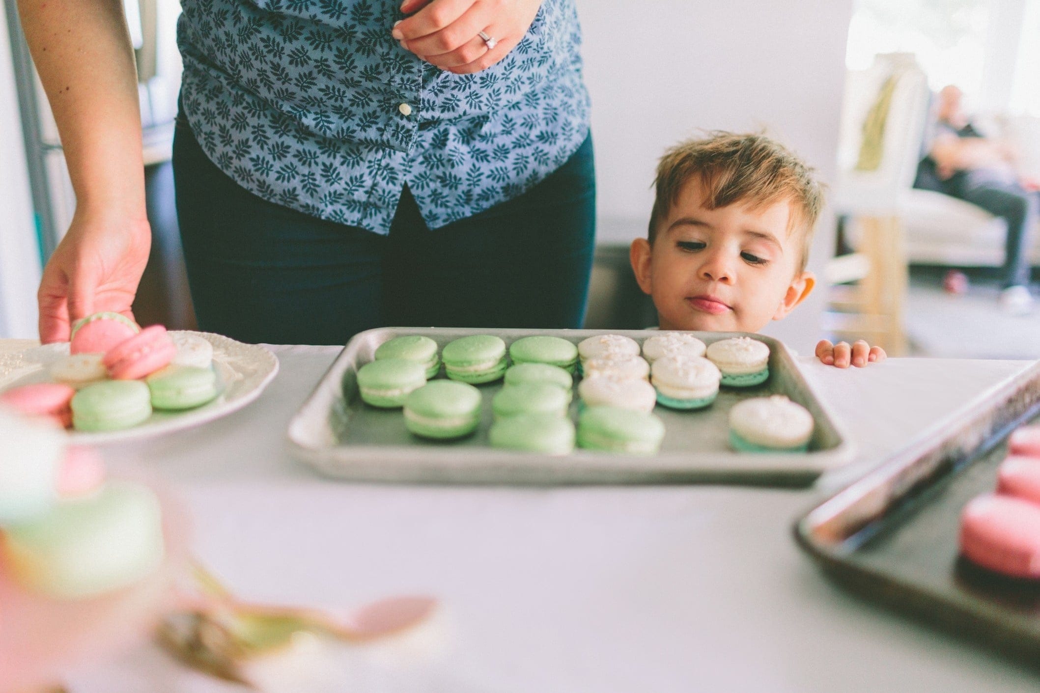 toddler in front of a sheet pan of macarons