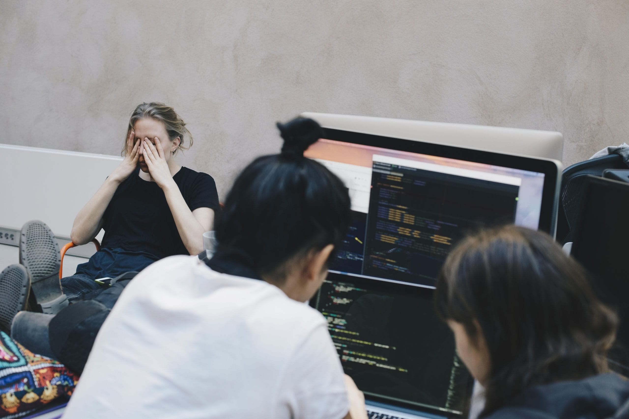 working mom covering her face in her hands at the office