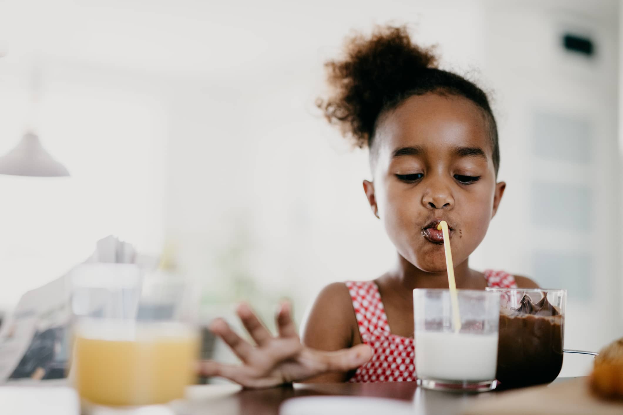 young girl drinking milk through a straw