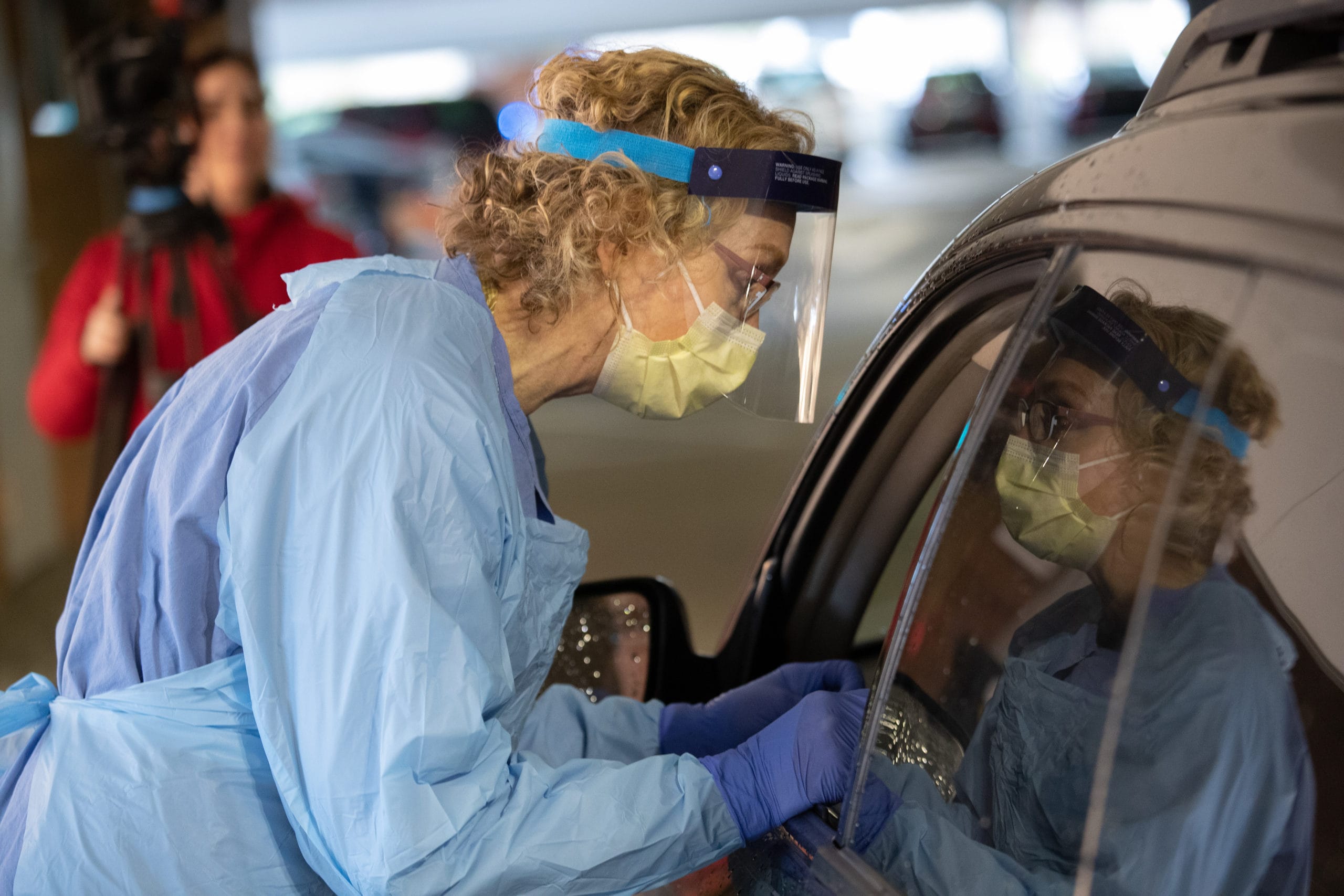 female nurse performing a drive-thru COVID test