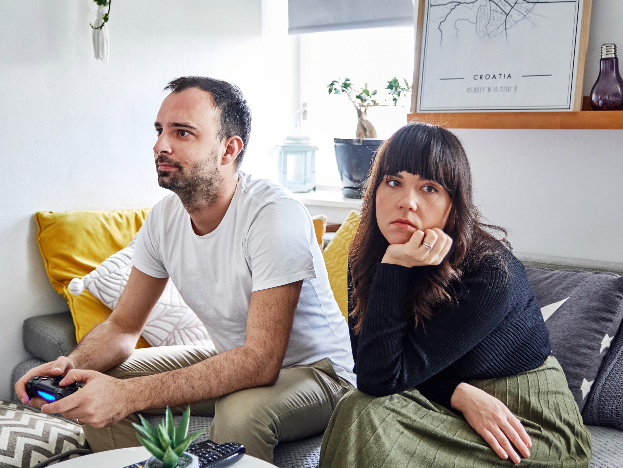 husband playing video game while wife is annoyed beside him