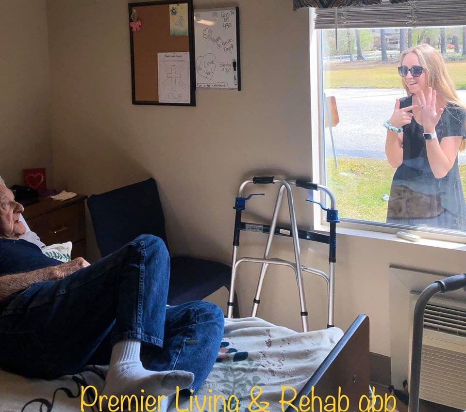 woman talking to old man outside a window