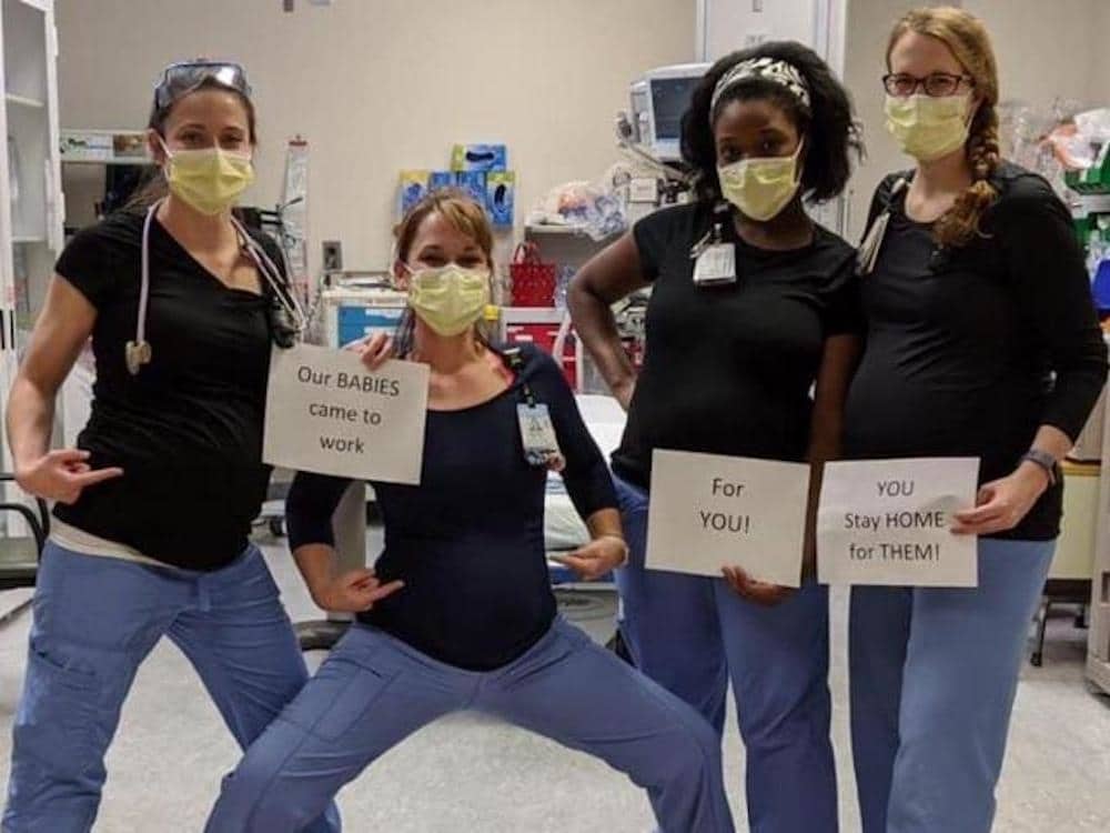 pregnant nurses holding signs asking people to stay home