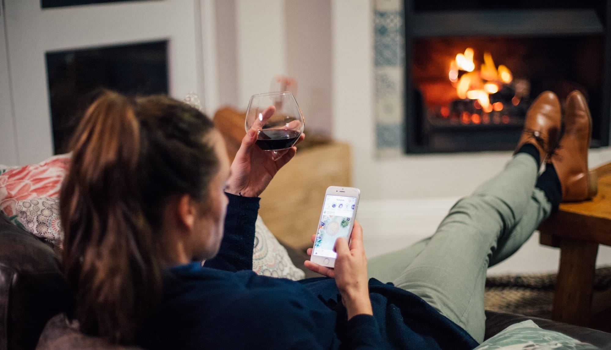 mom scrolling on her phone while holding a glass of wine