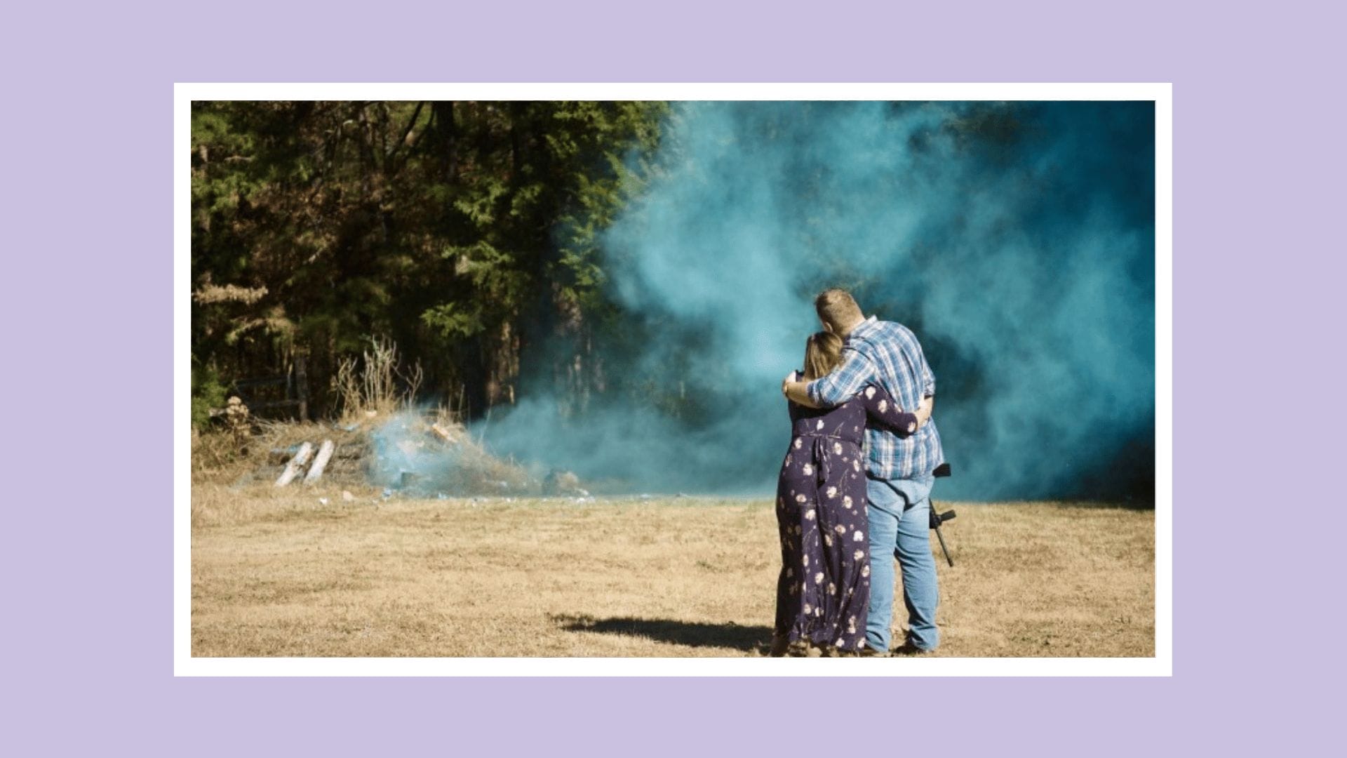 couple overlooking blue smoke for a gender reveal