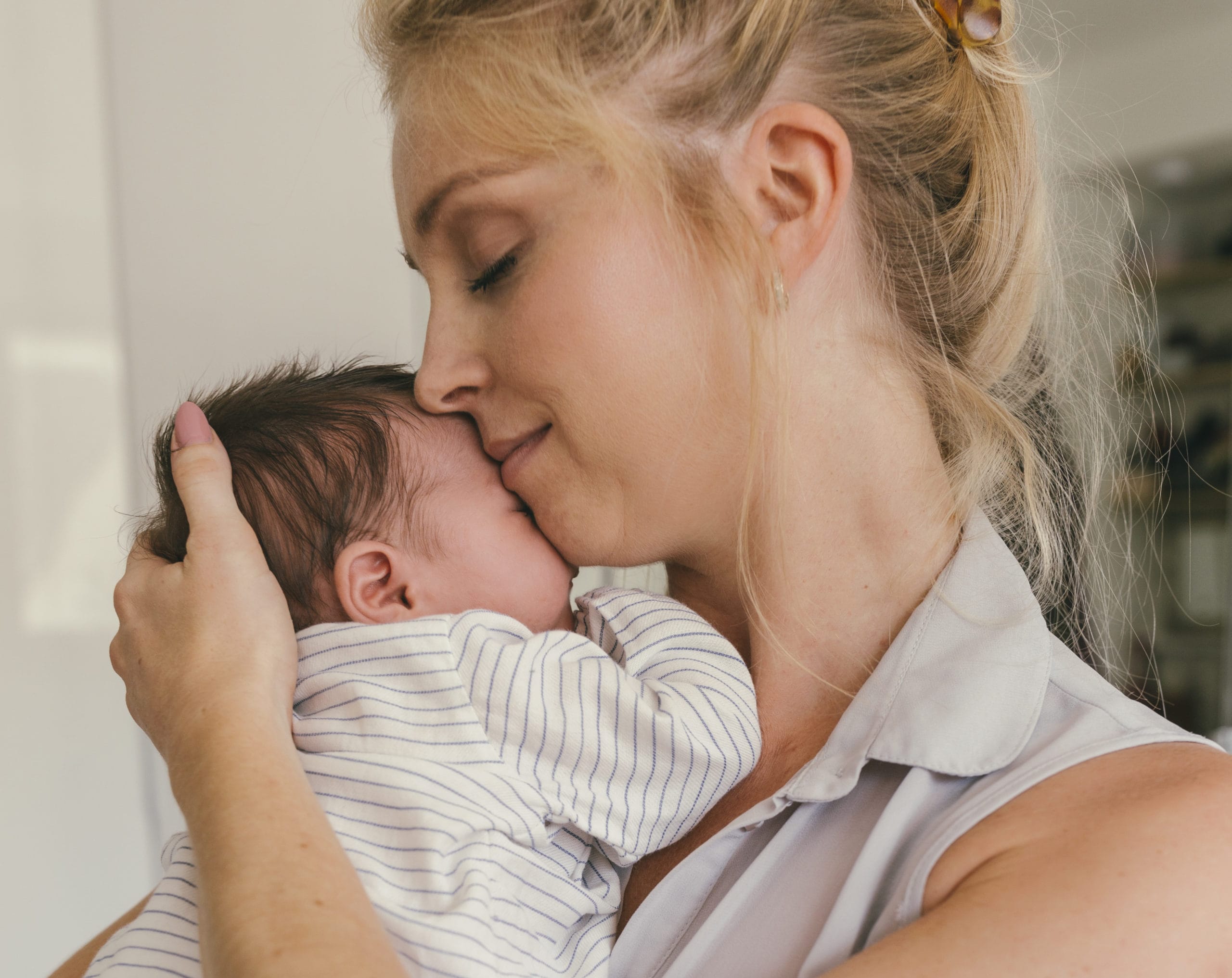 mom snuggling newborn baby against her cheek