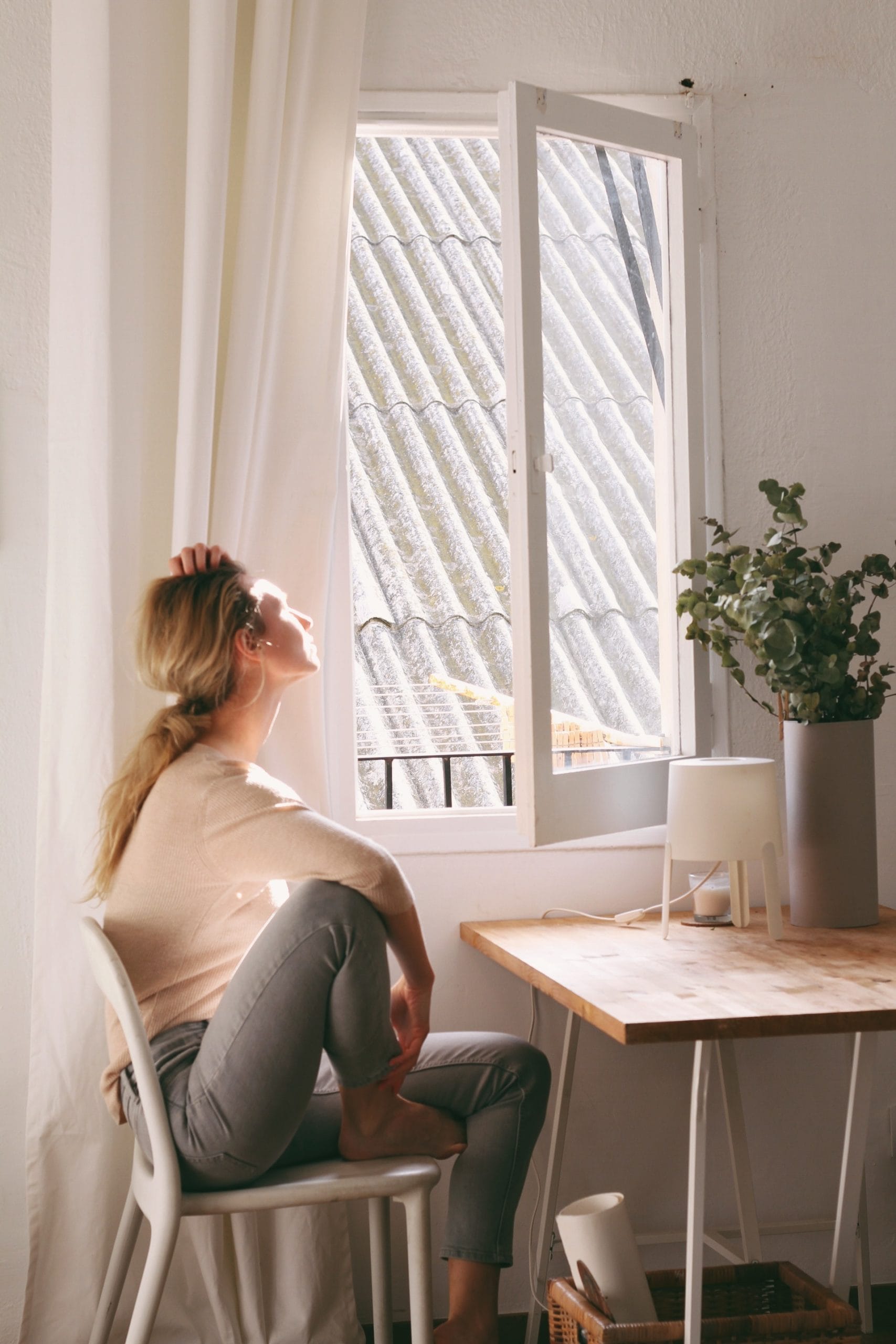 woman sitting at desk staring out the window - thinking about trying to conceive after miscarriage