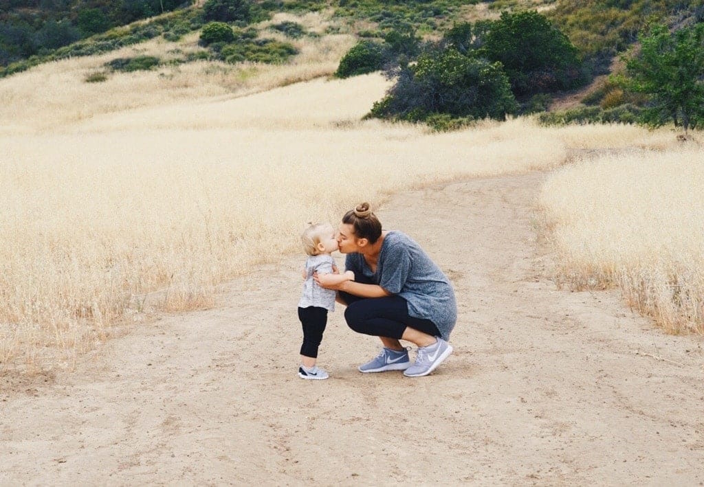 mom kissing child outside