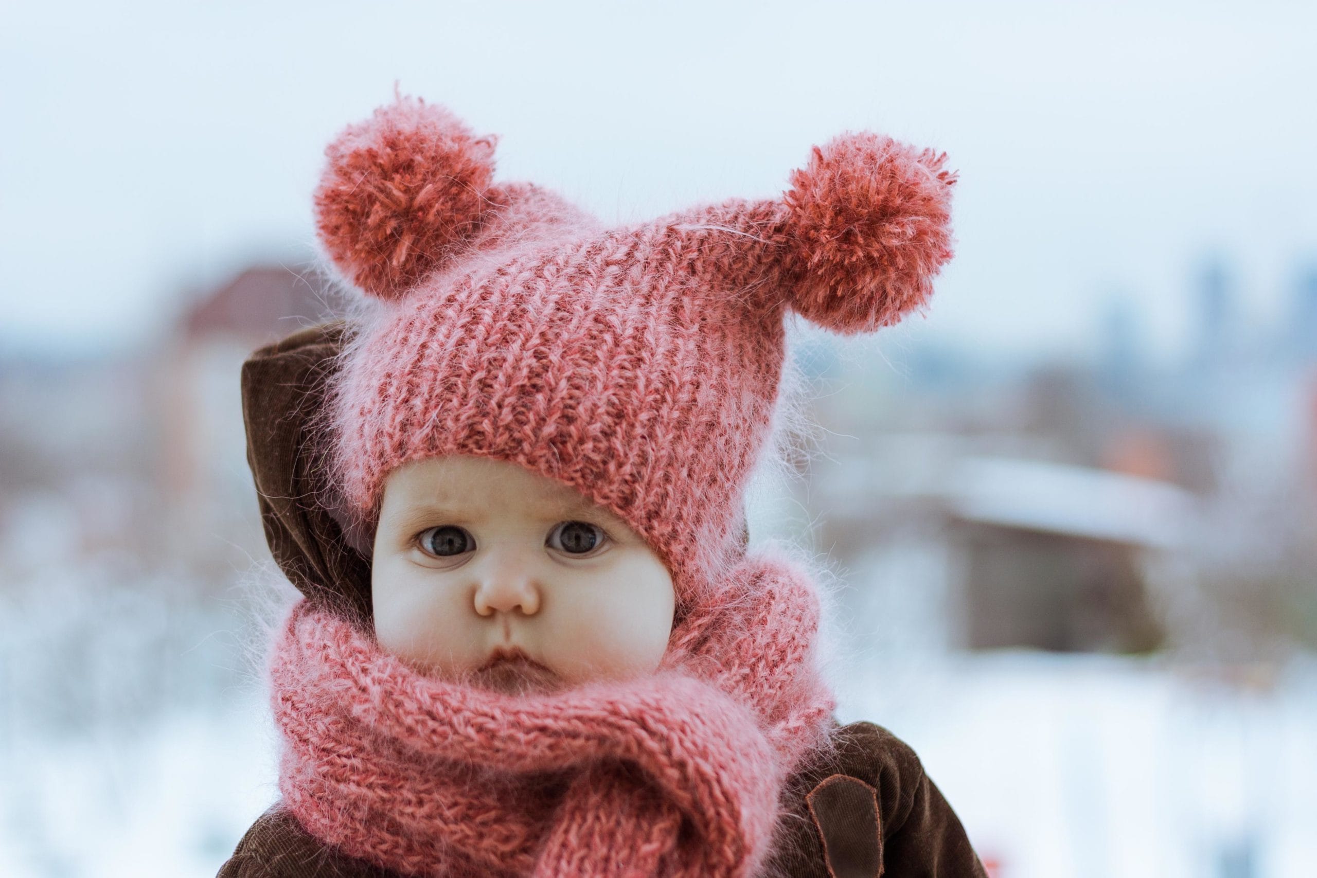 little girl wearing pink beanie and pink scarf in the snow- january baby names