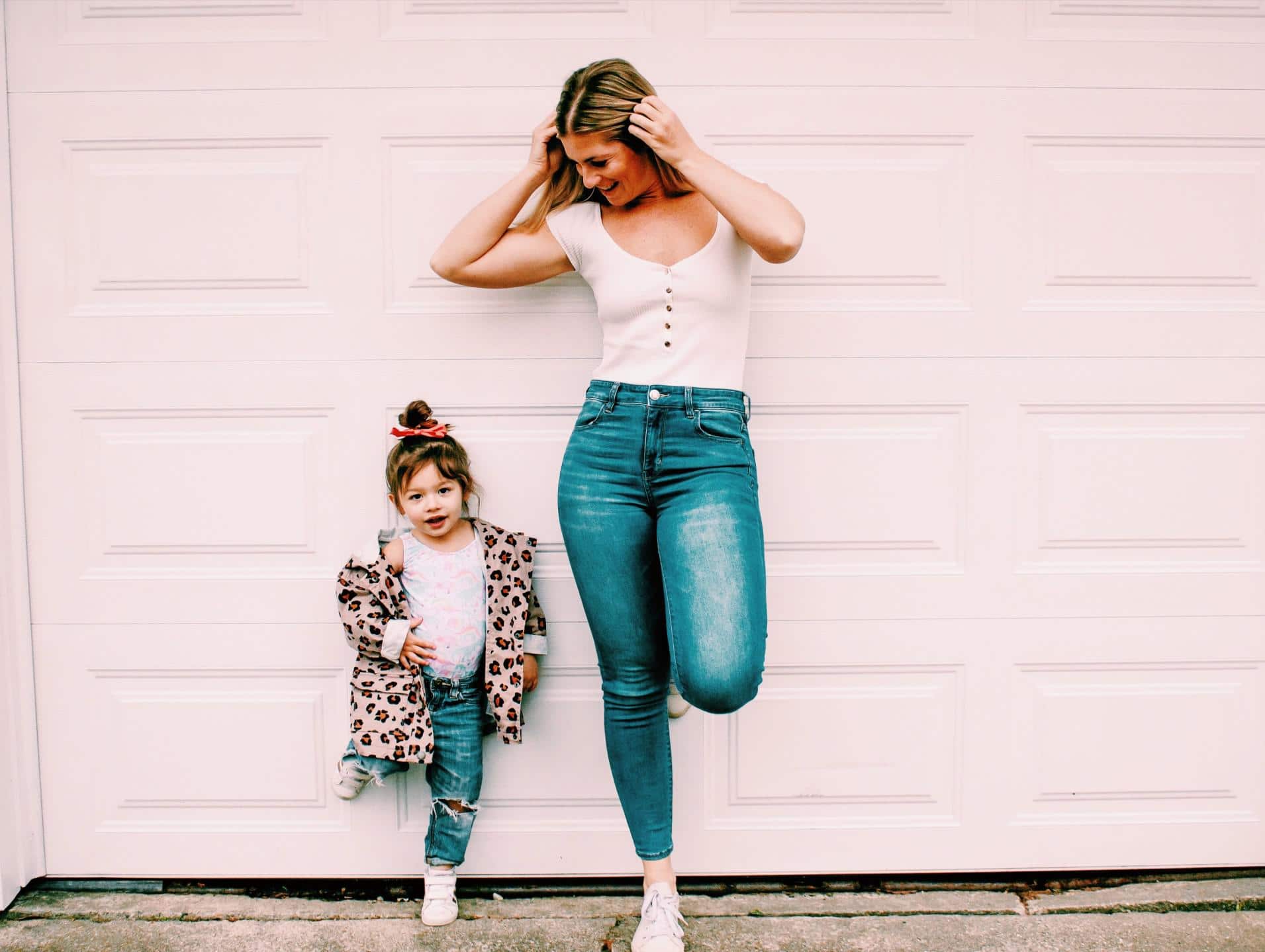 mom and daughter leaning against a brick wall