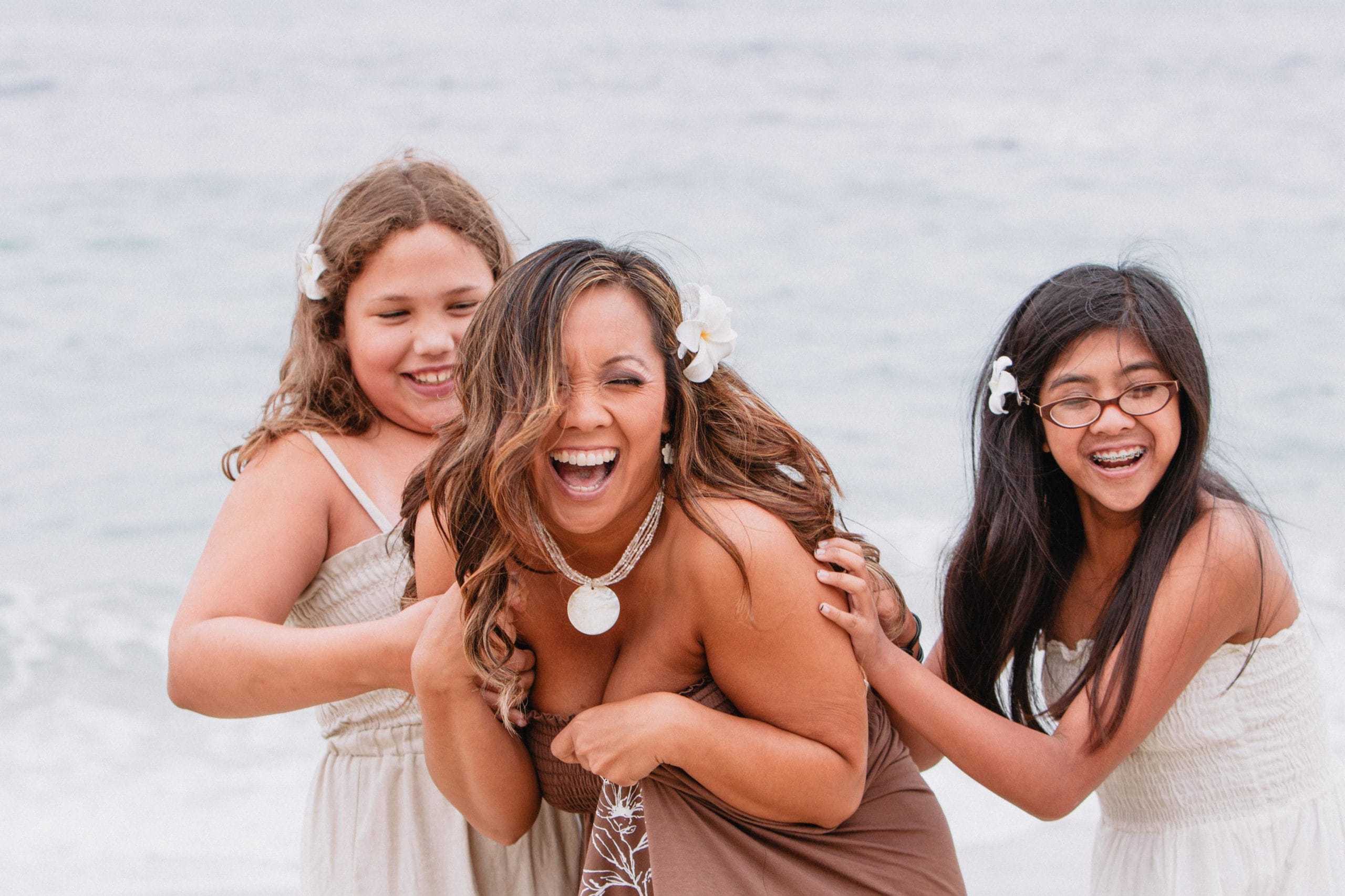 woman laughing with daughters on the beach