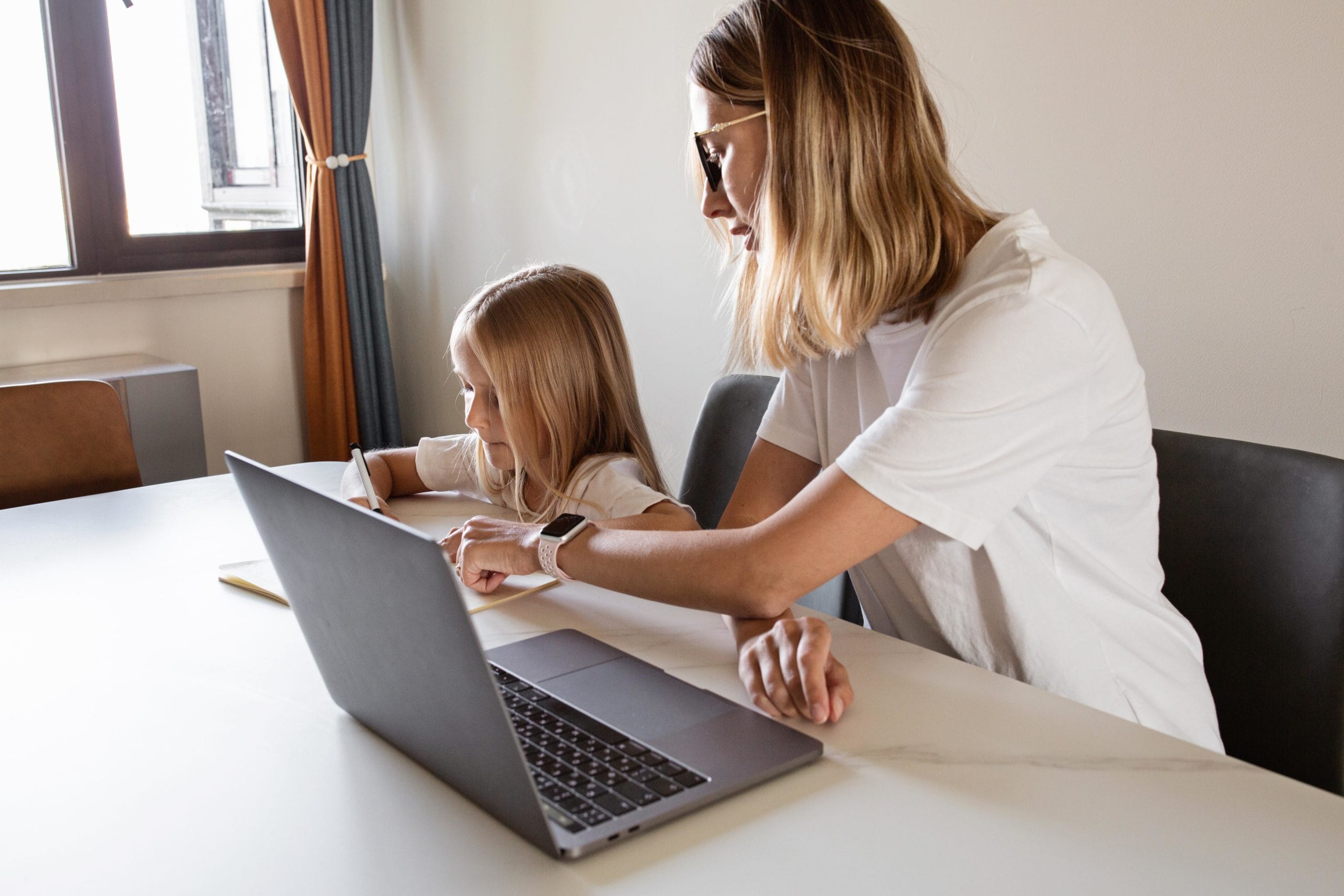 mom working on a computer with daughter beside her