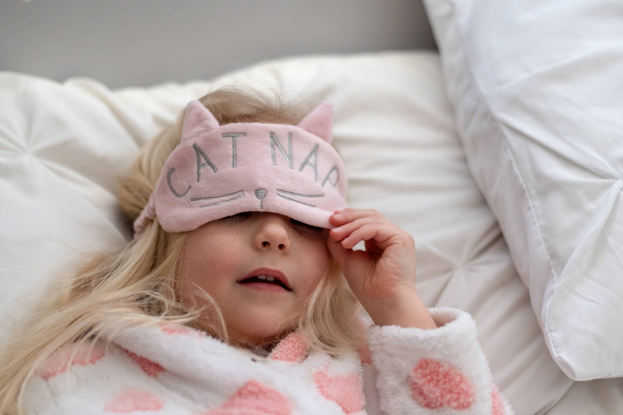 little girl wearing an eye mask in bed