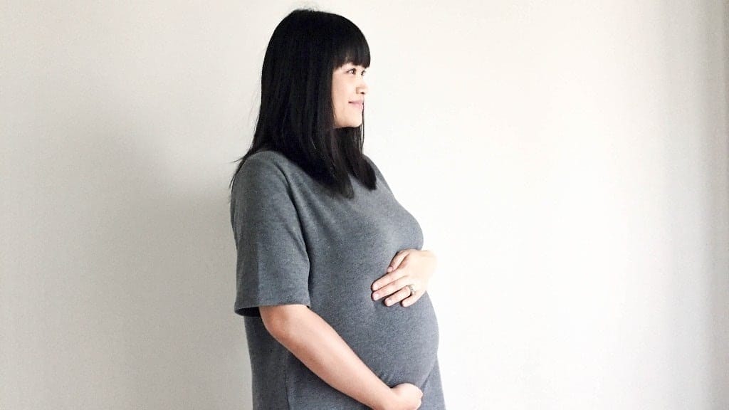 pregnant woman hugging her belly - what your body is doing in the third trimester