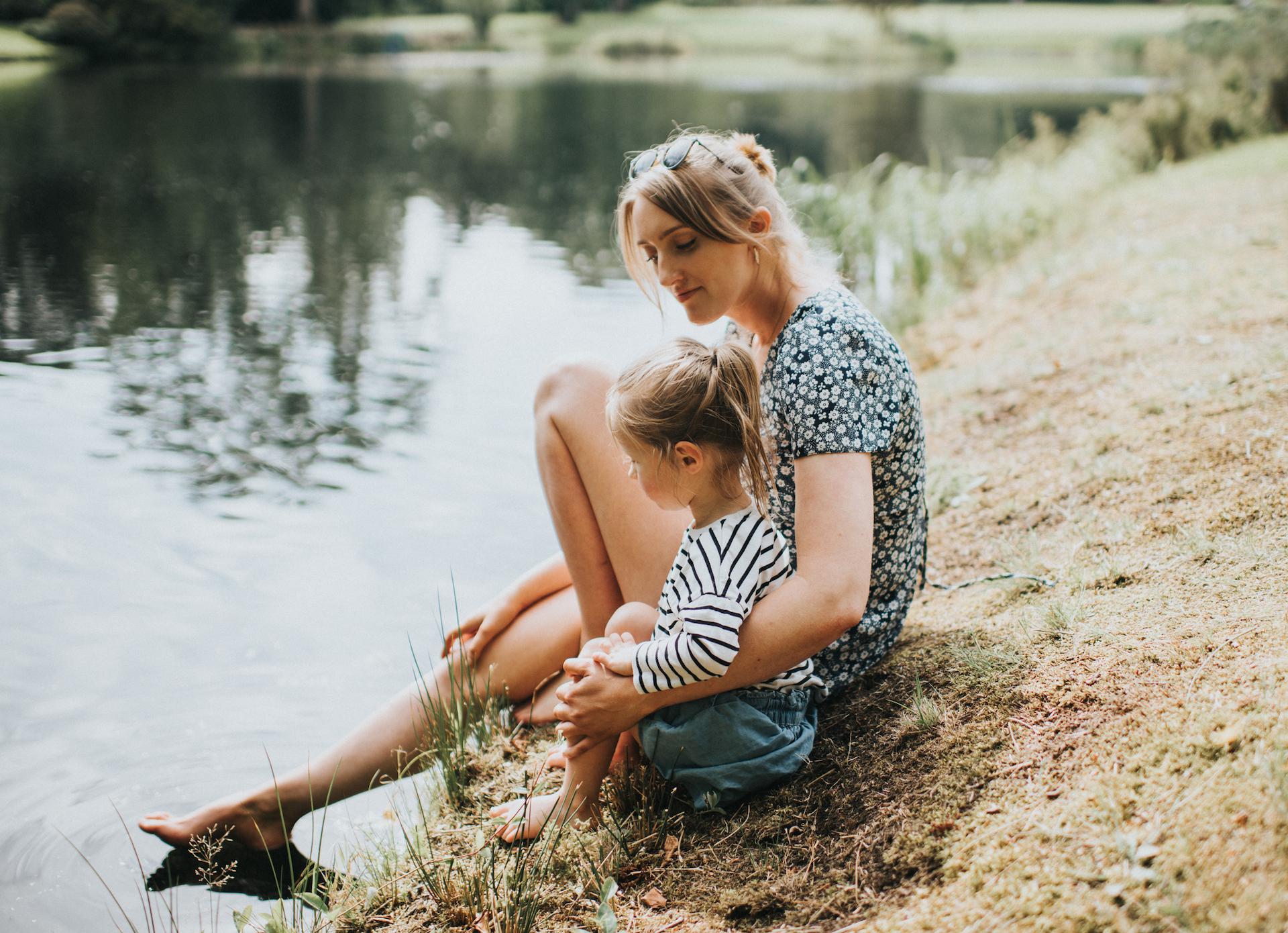 mom and daughter sitting beside a lake- busy mom summer