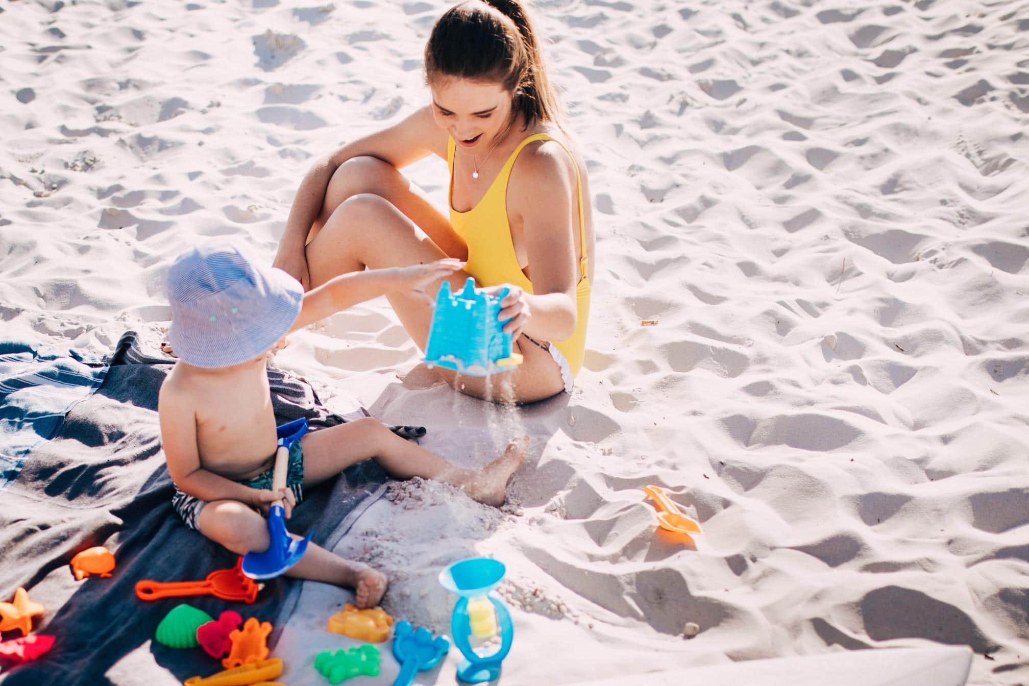 mom and child playing with toys on the sand- beach safety tips