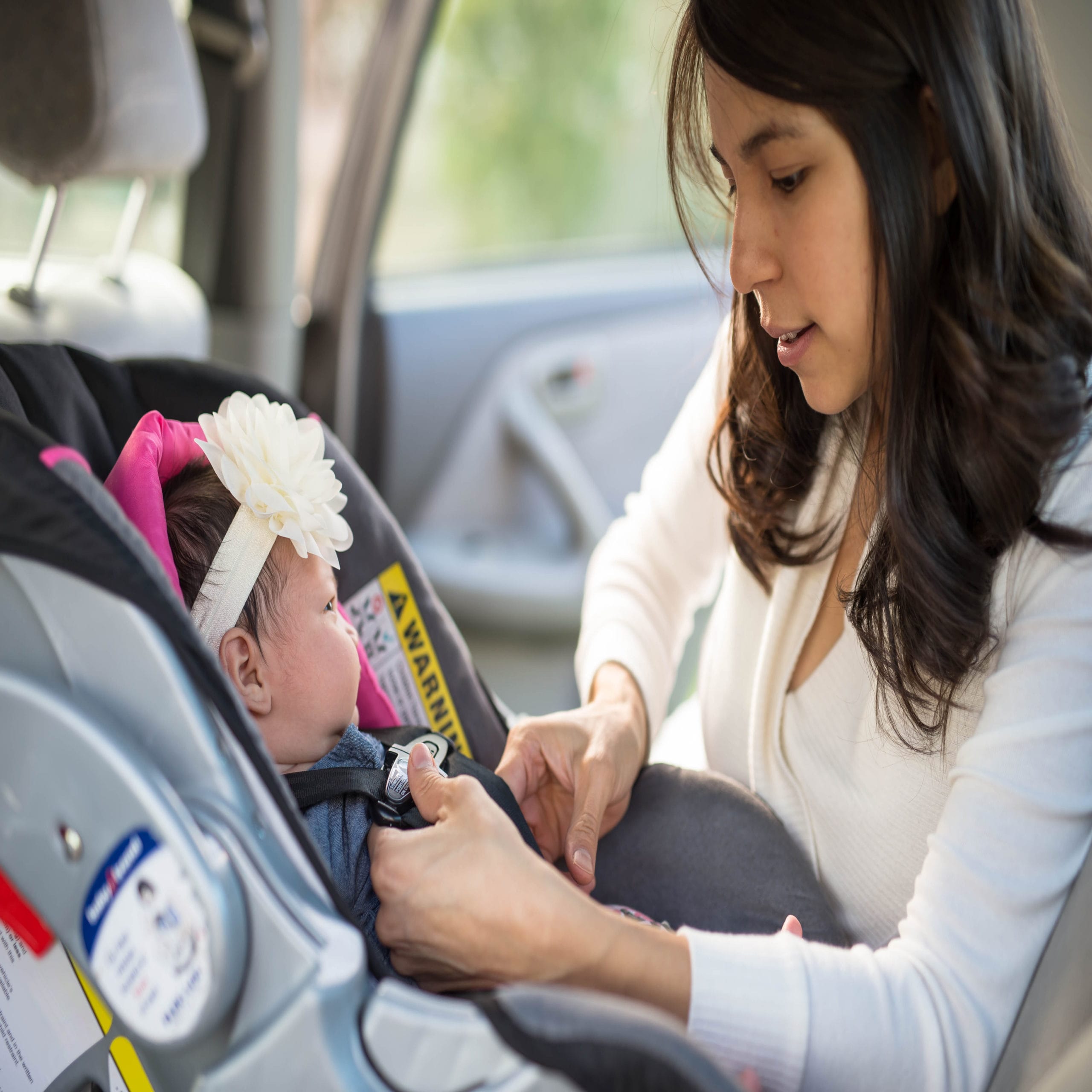 mom putting baby in car seat - are car seat accessories safe