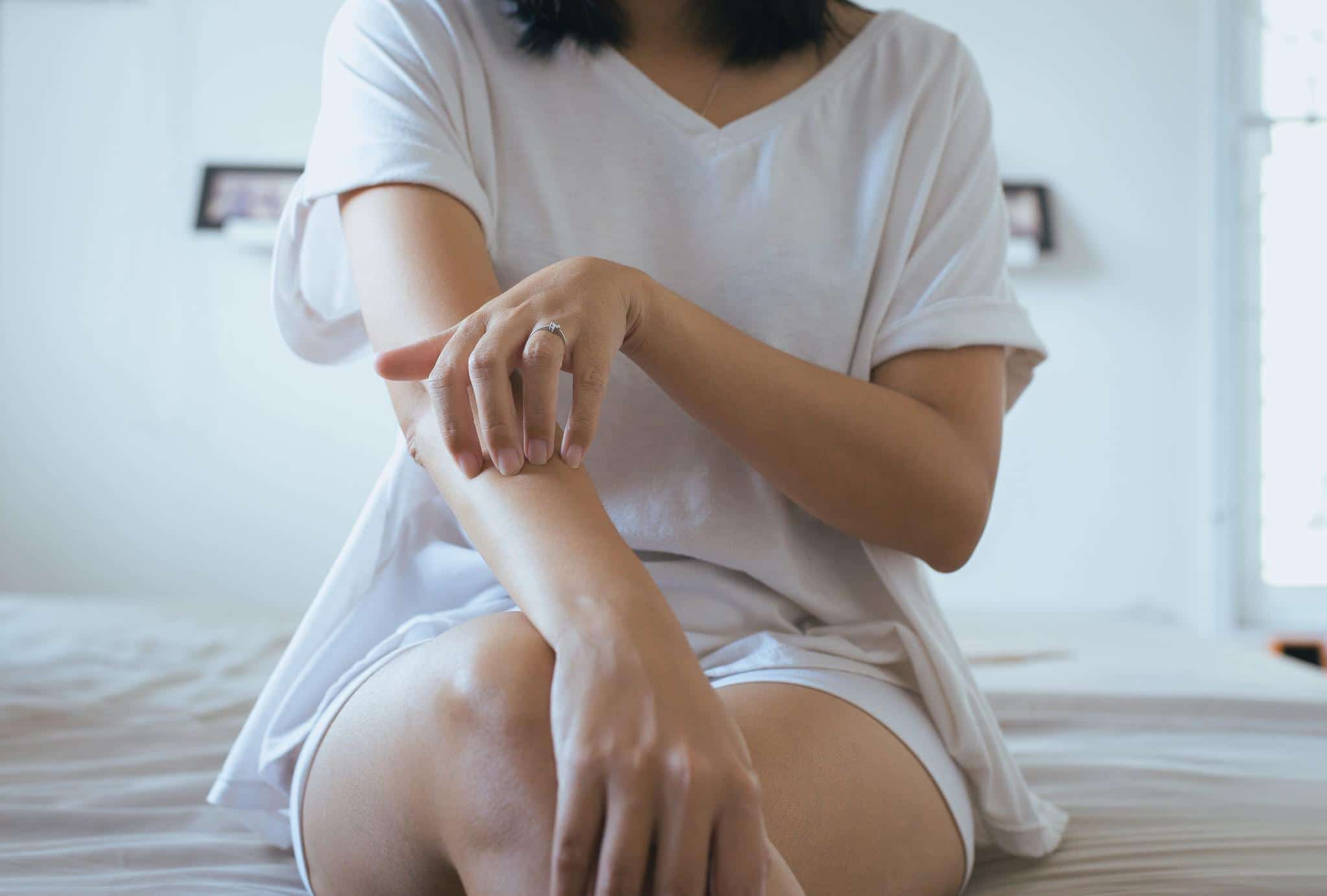 woman scratching her arm, one of the possible epidural side effects