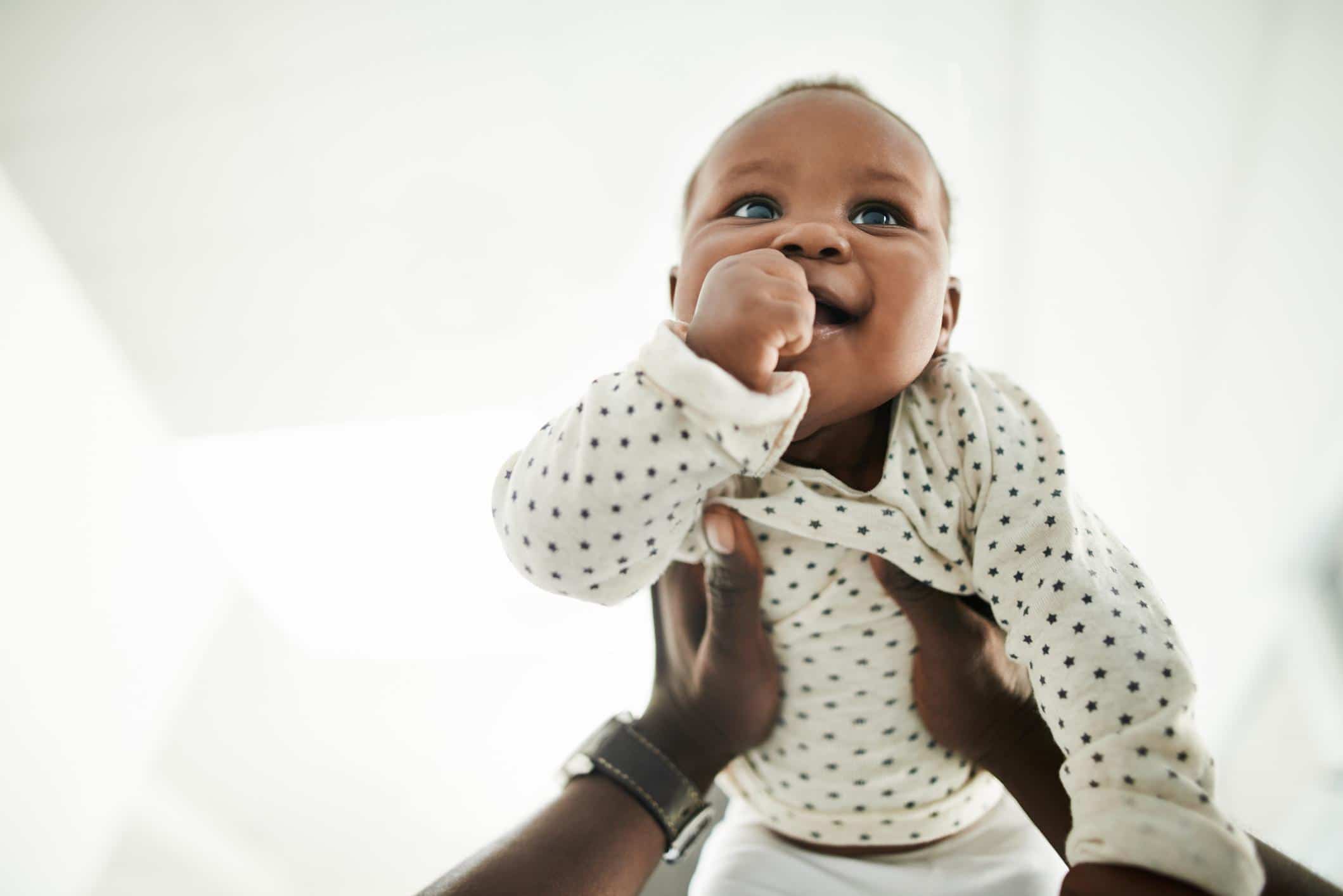 dad holding up baby in the air- august baby names