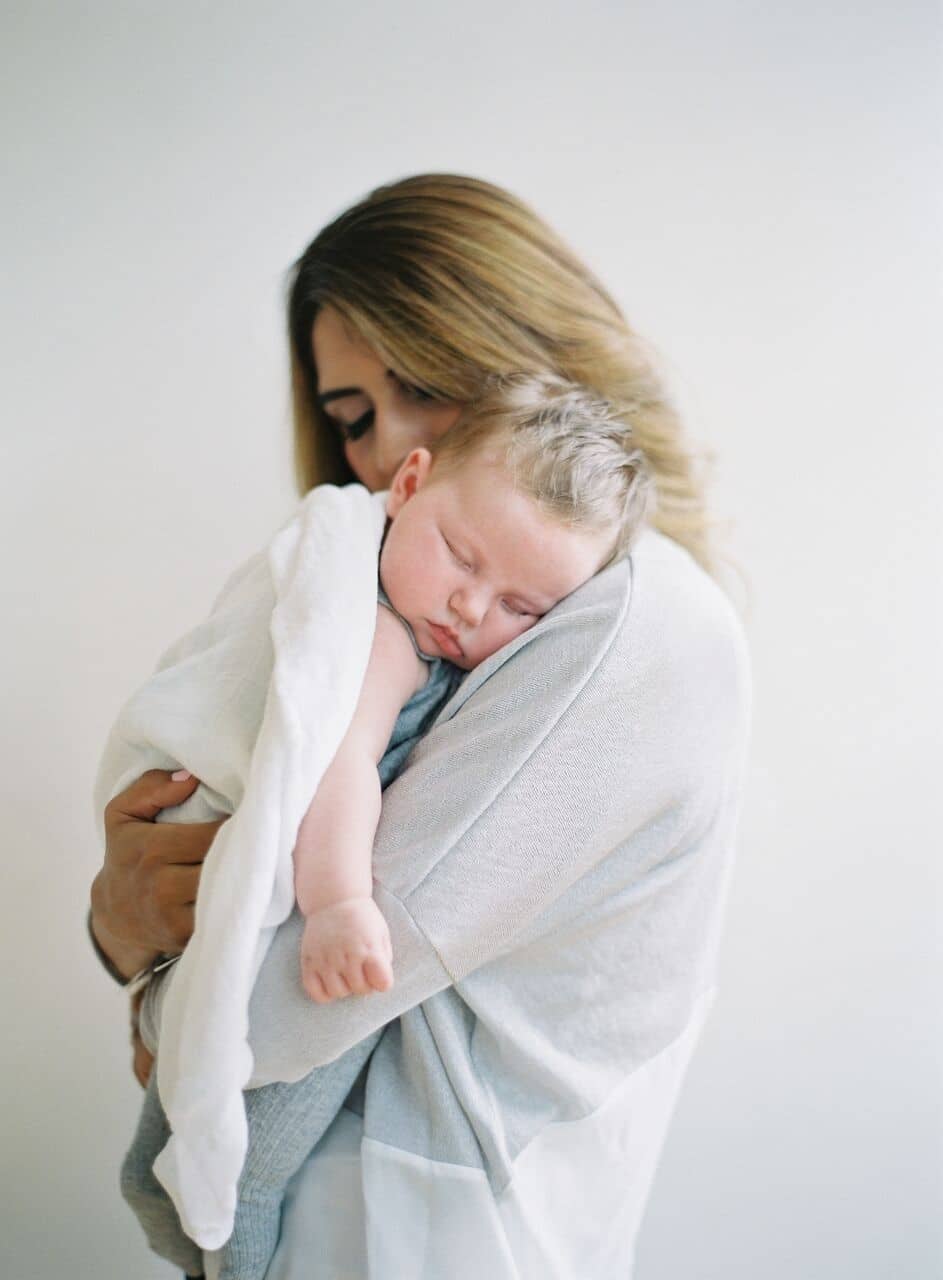 mom snuggling sleeping baby on her shoulder