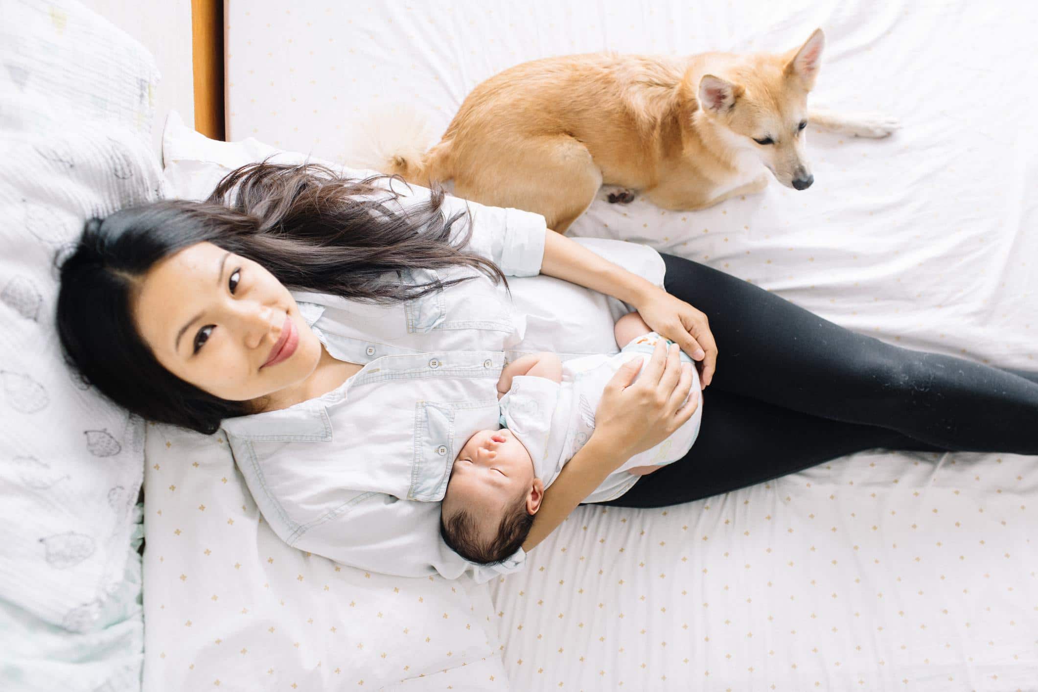 mom holding baby and looking at camera practicing postpartum rest