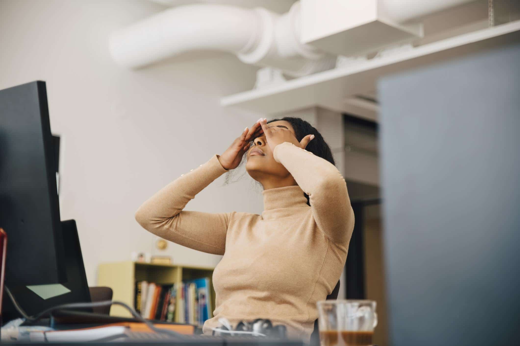 woman sitting at desk rubbing eyes