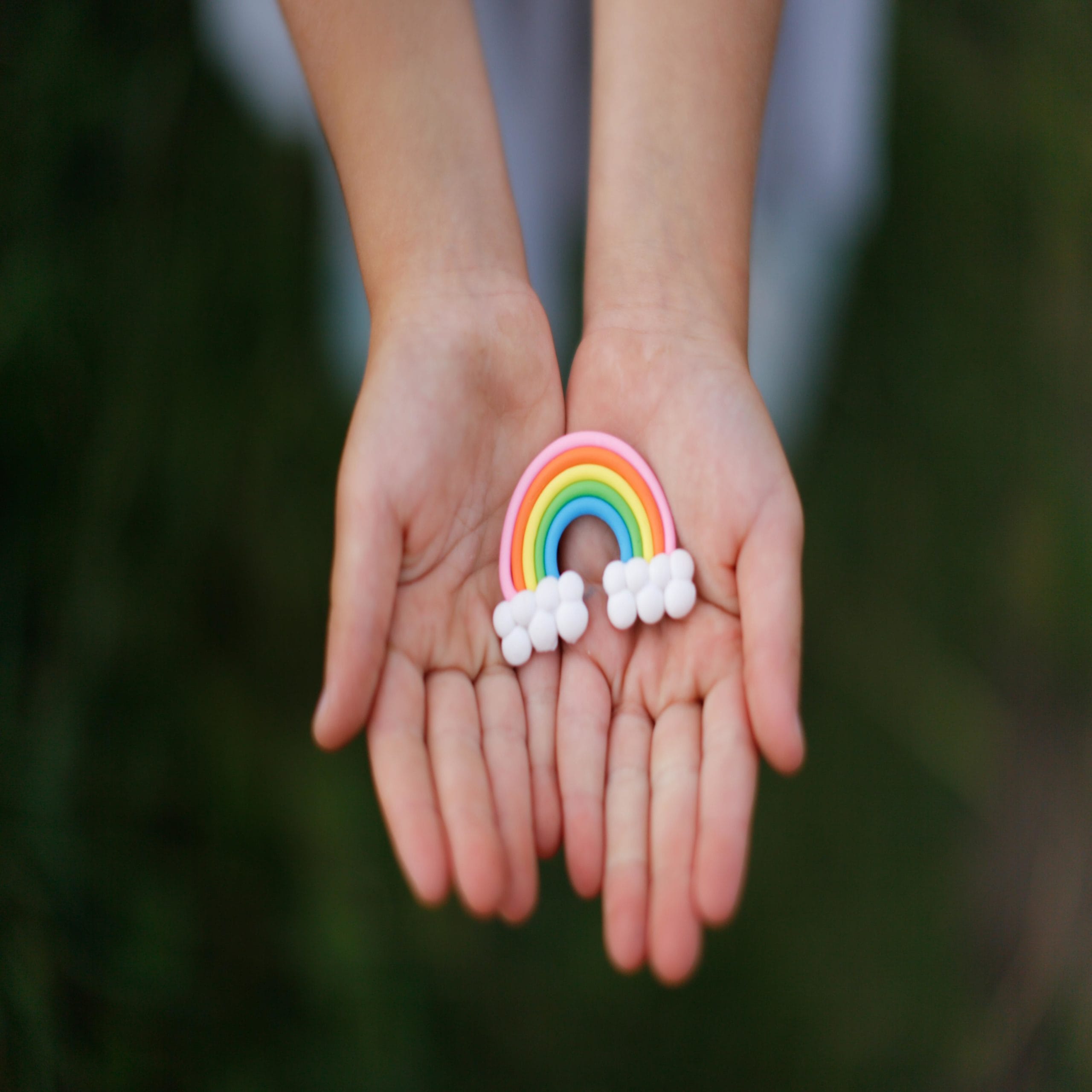 hands holding a rainbow toy