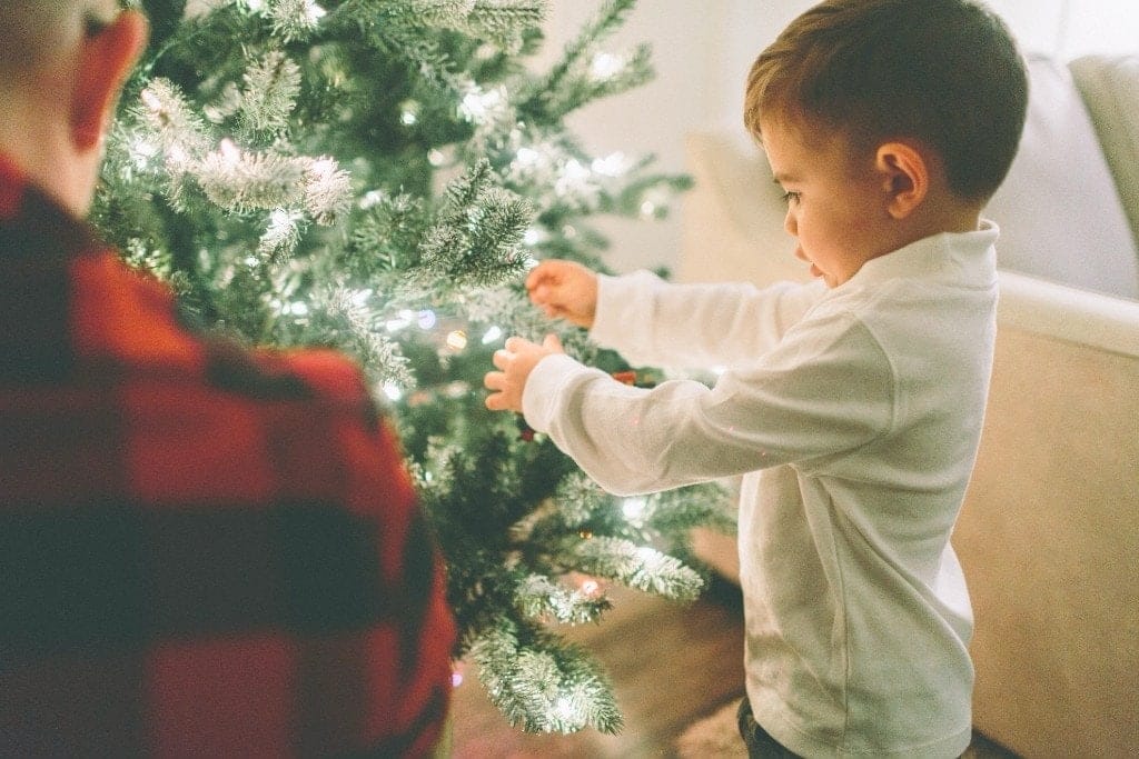 a child standing next to a christmas tree