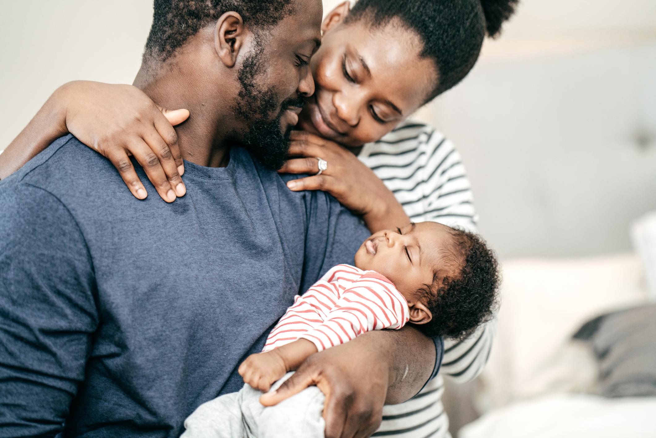 husband and wife looking at newborn baby