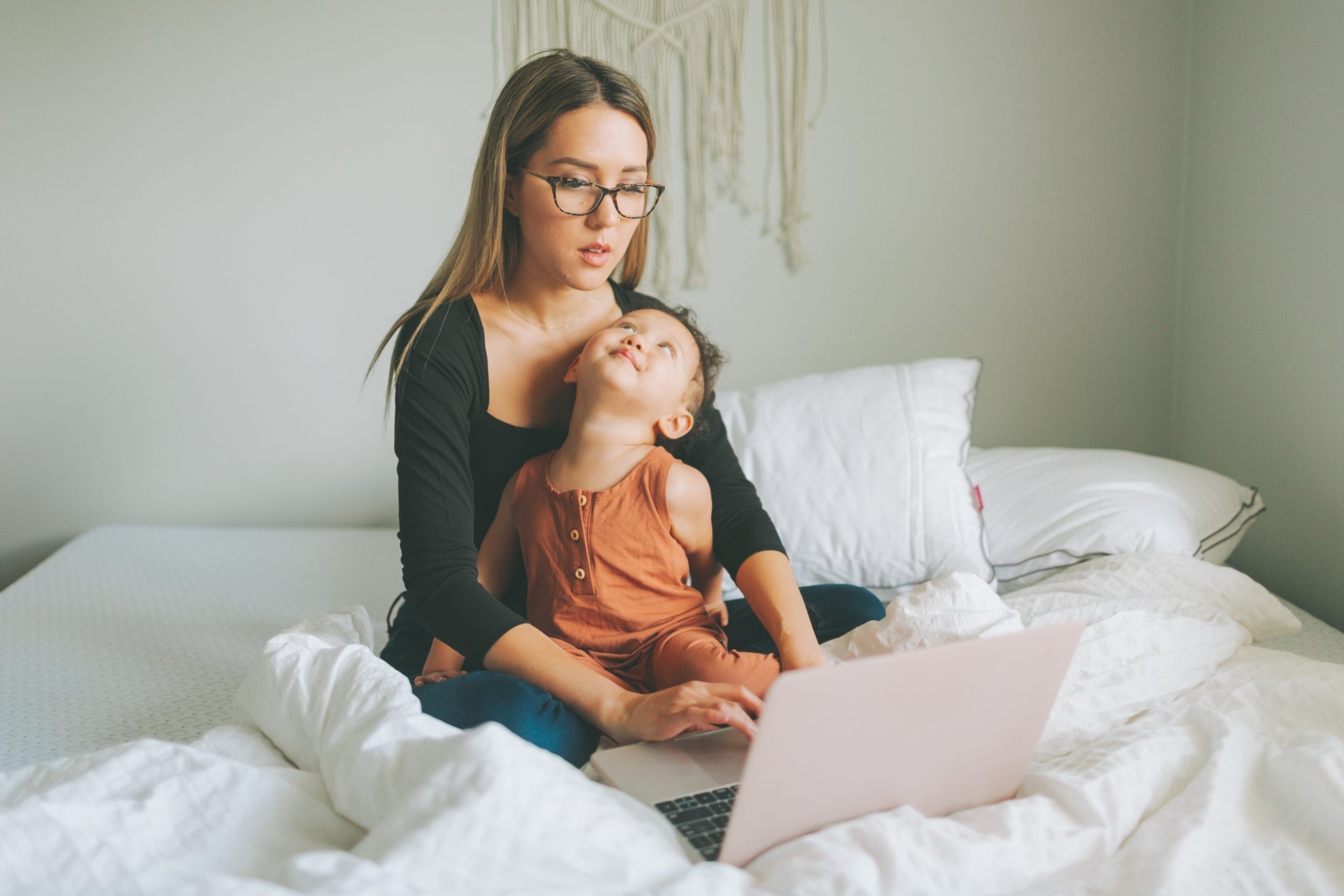 mom holding daughter on lap while she works