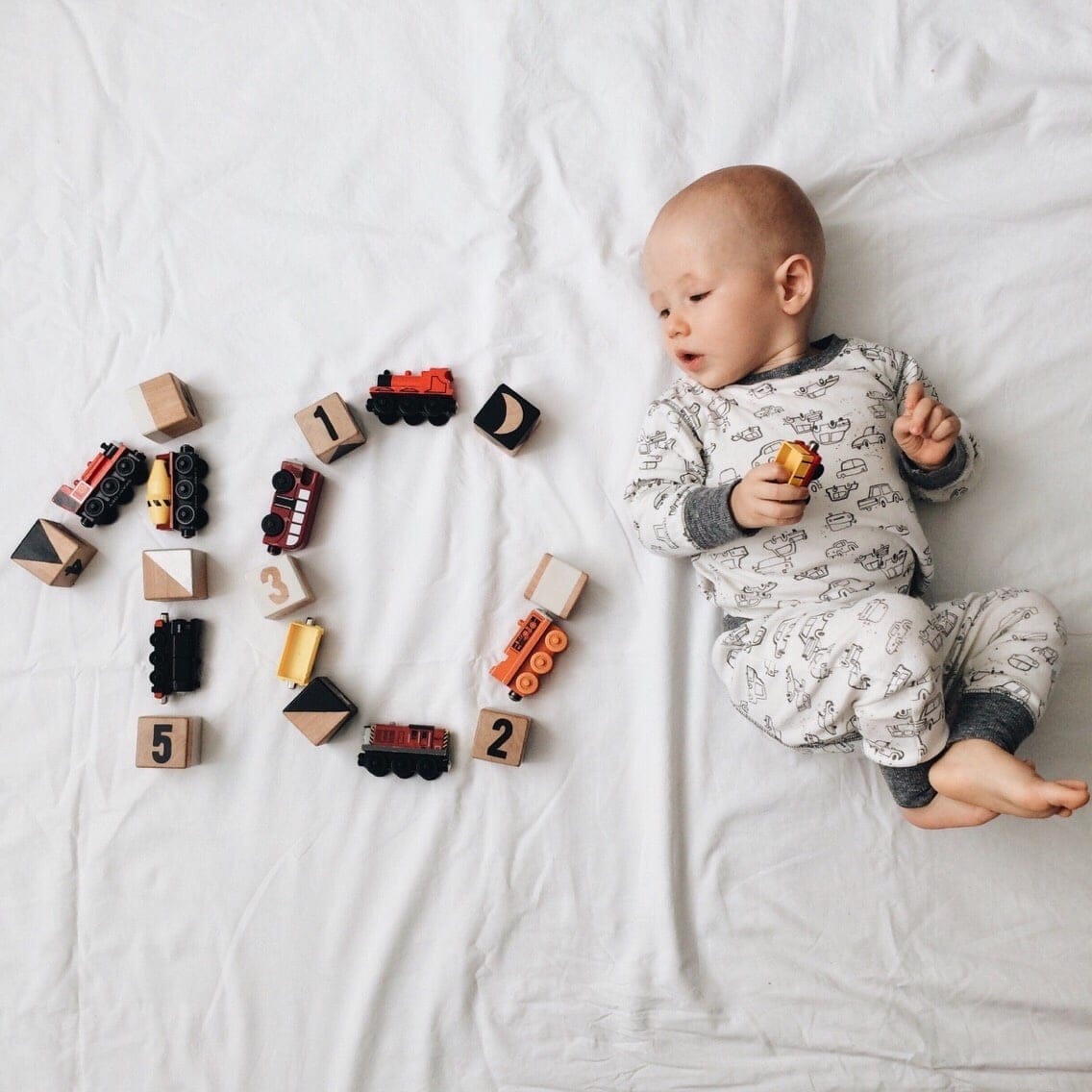 baby boy laying next to toys