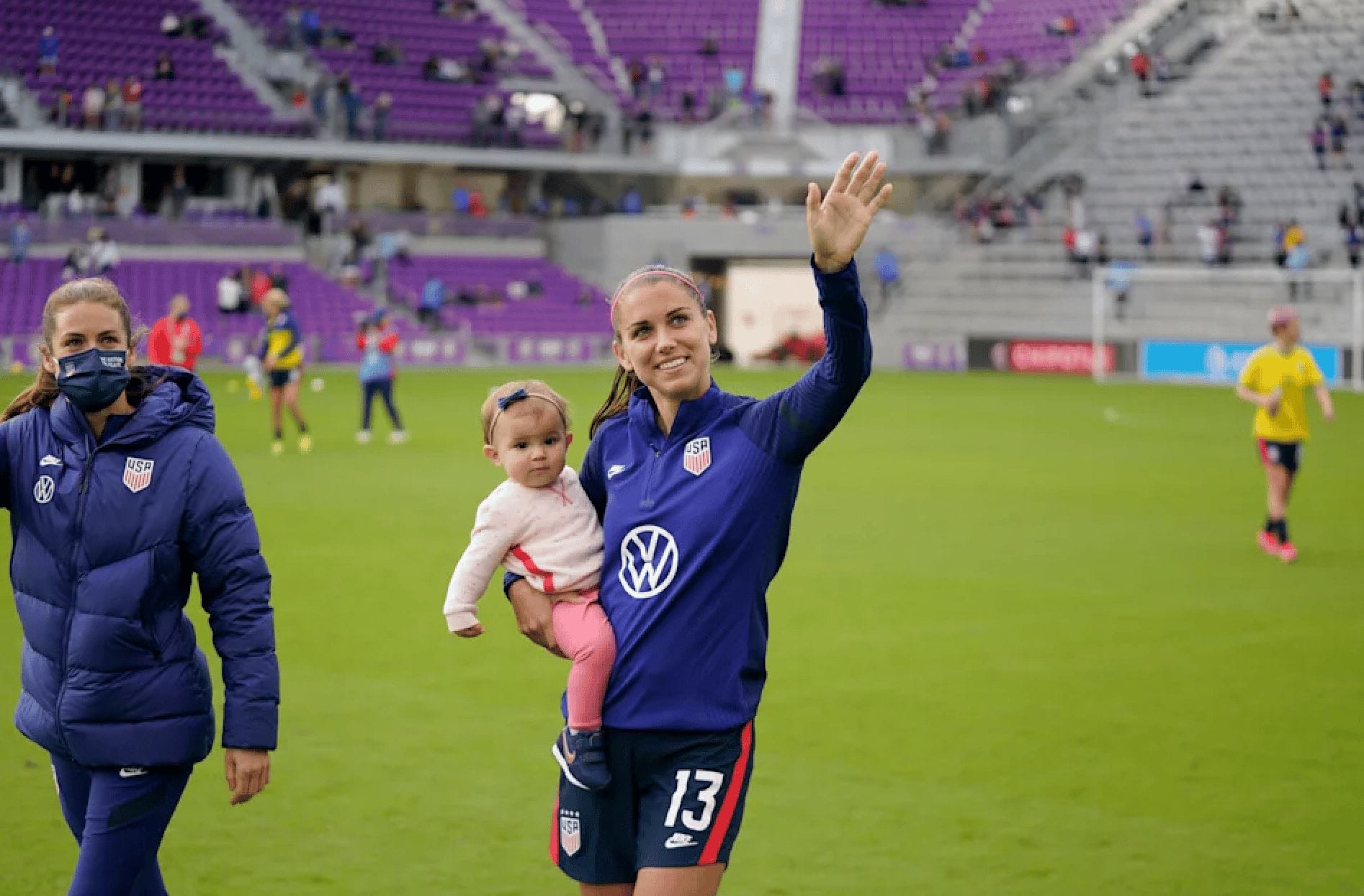 Olympic soccer athlete holding her baby on the field