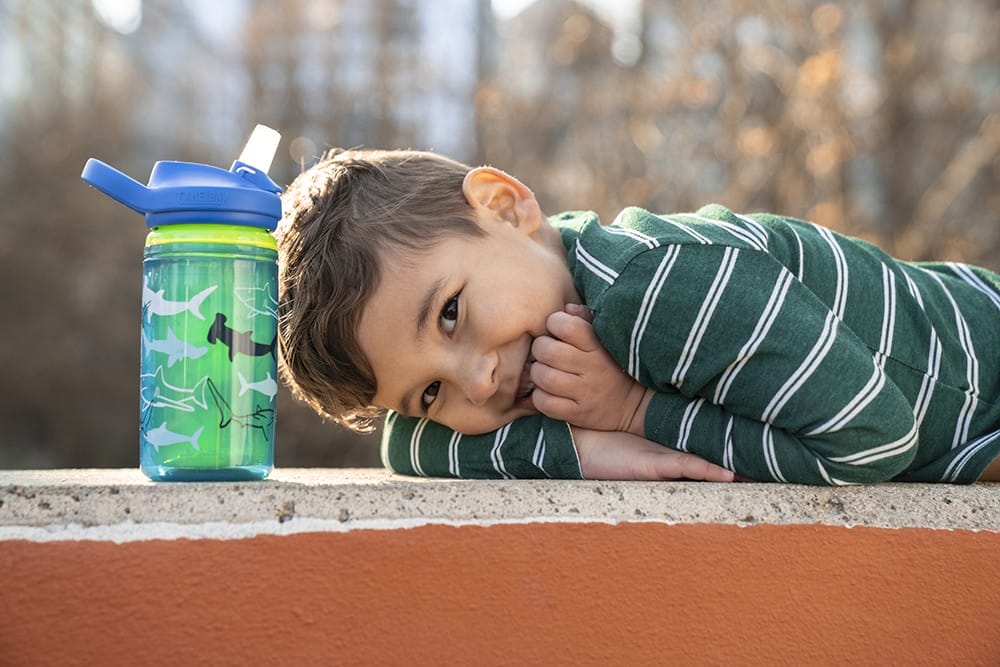 kid sitting at a park table with a water bottle