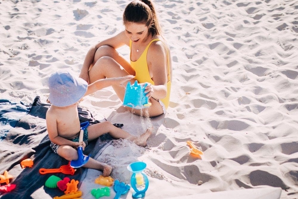 mom and son playing with sand on the beach, thinking about the psychological benefits of family vacations