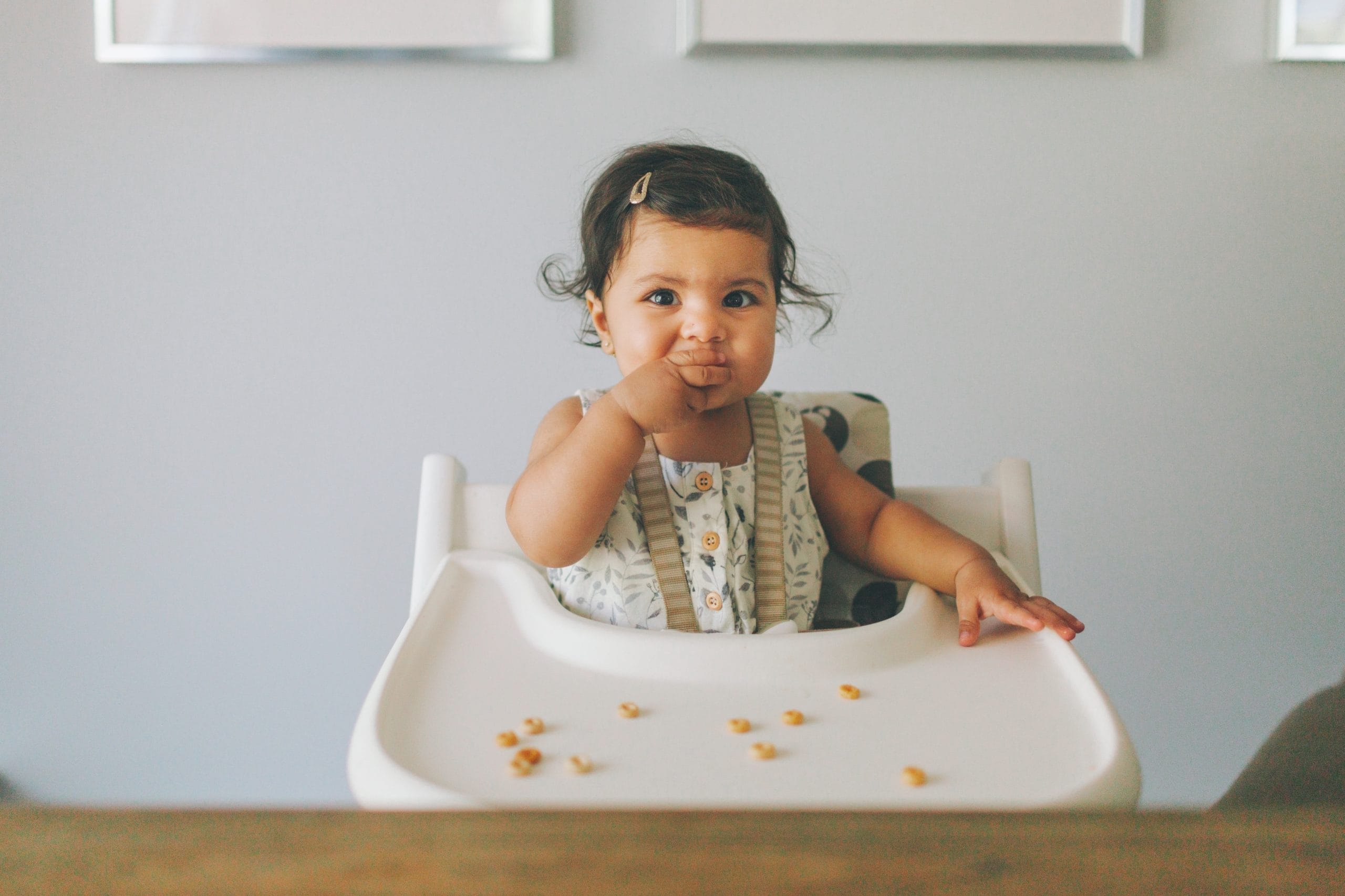 baby eating solid food in a high chair