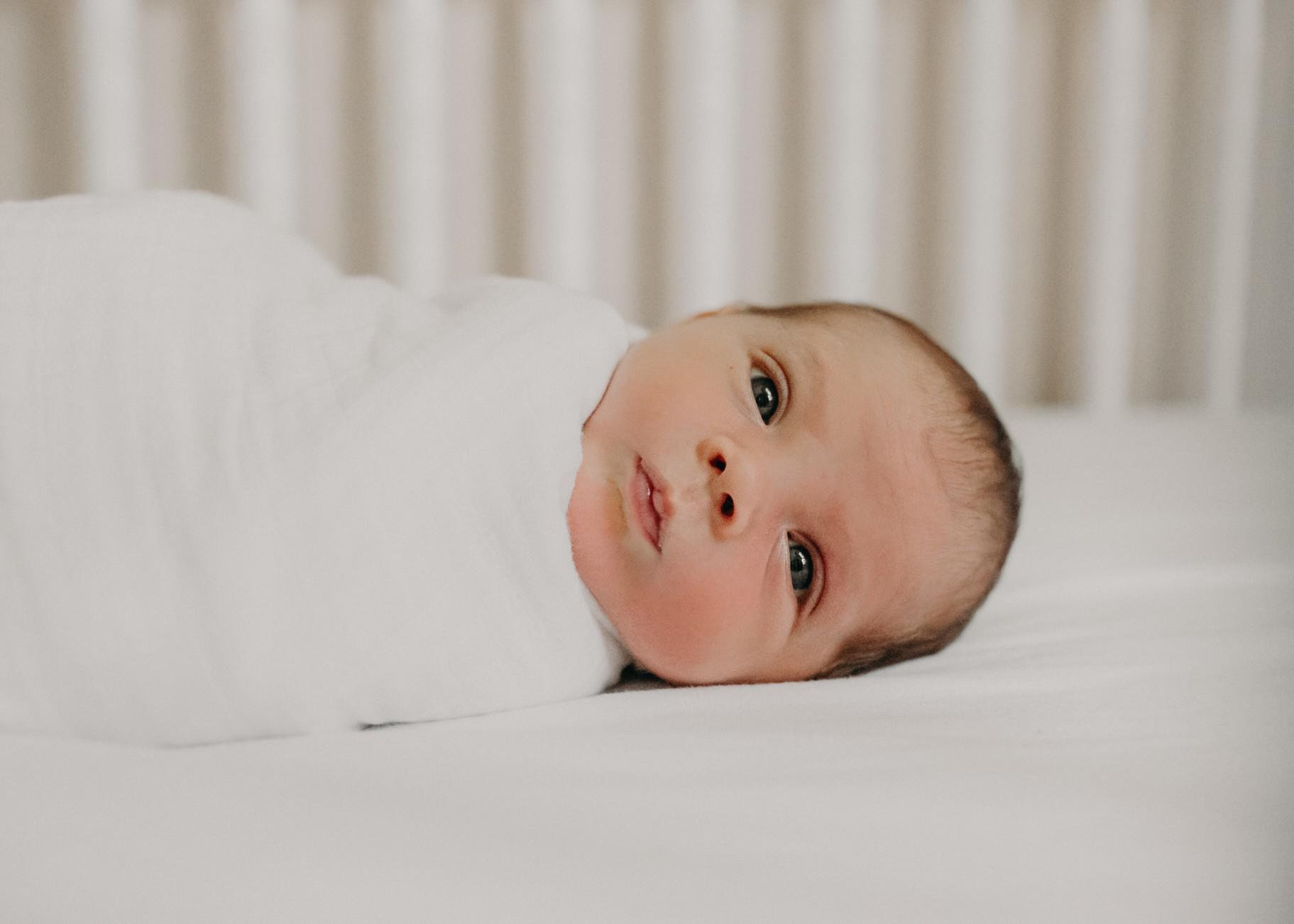 baby swaddled in a crib - 1-week-old baby feeding schedule