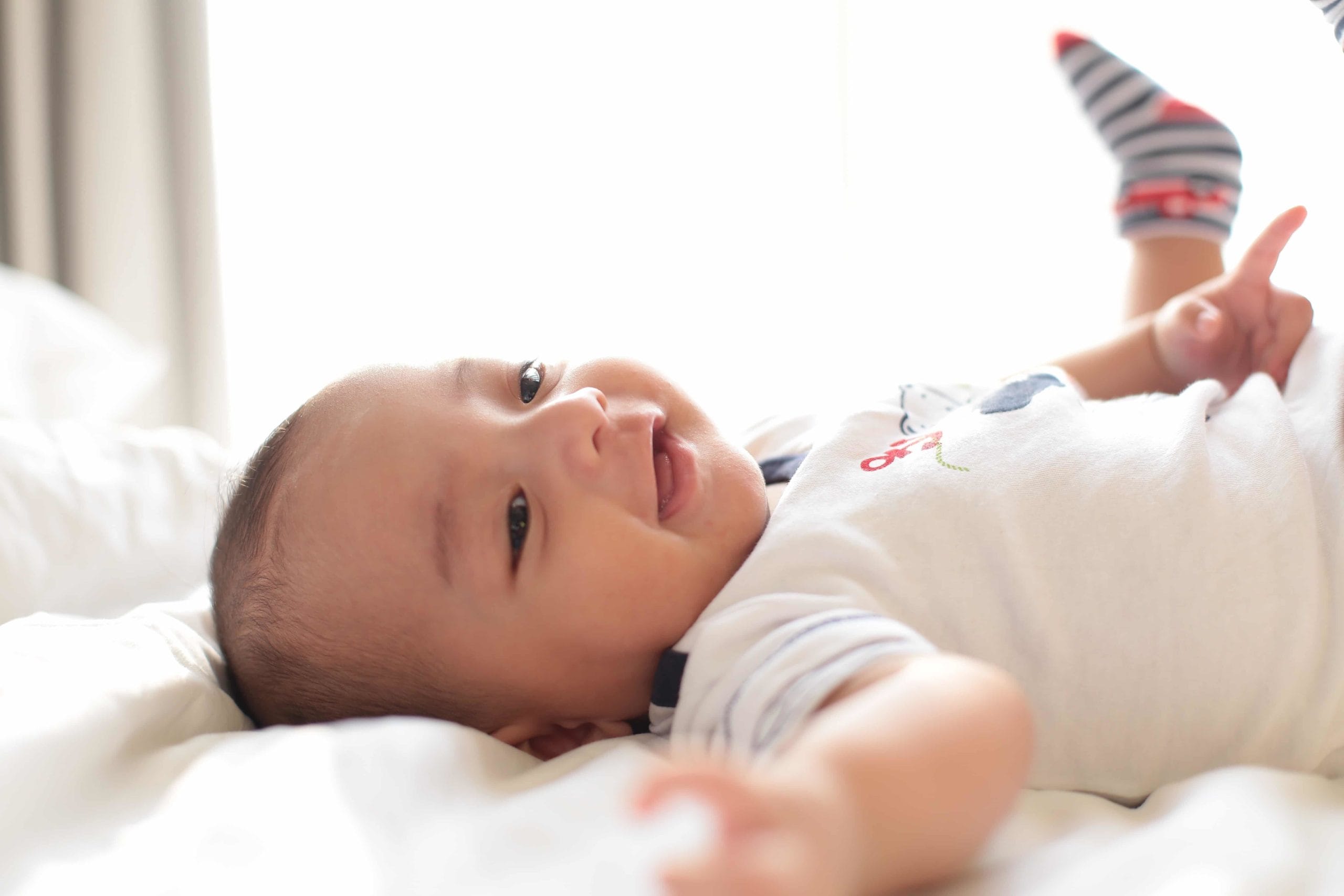 baby lying down on bed and smiling - activities for 5-month-old