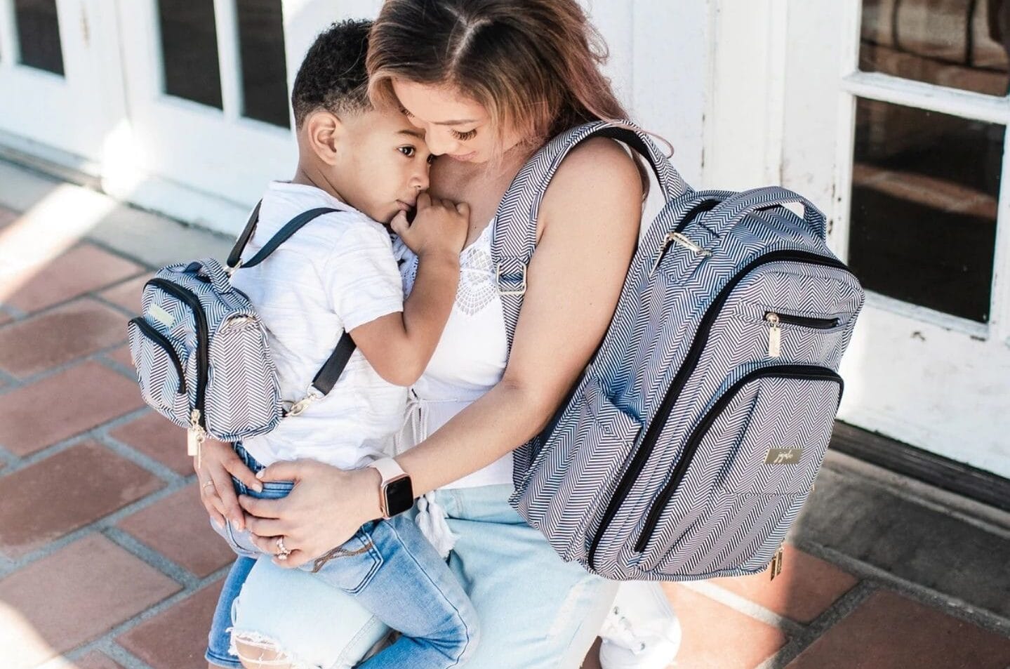 mom holding a toddler while wearing a diaper bag