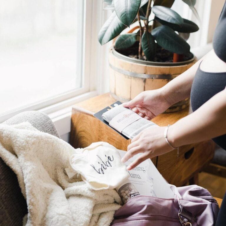 mom touching newborn baby in a hospital bed - What we wish we packed in our hospital bags