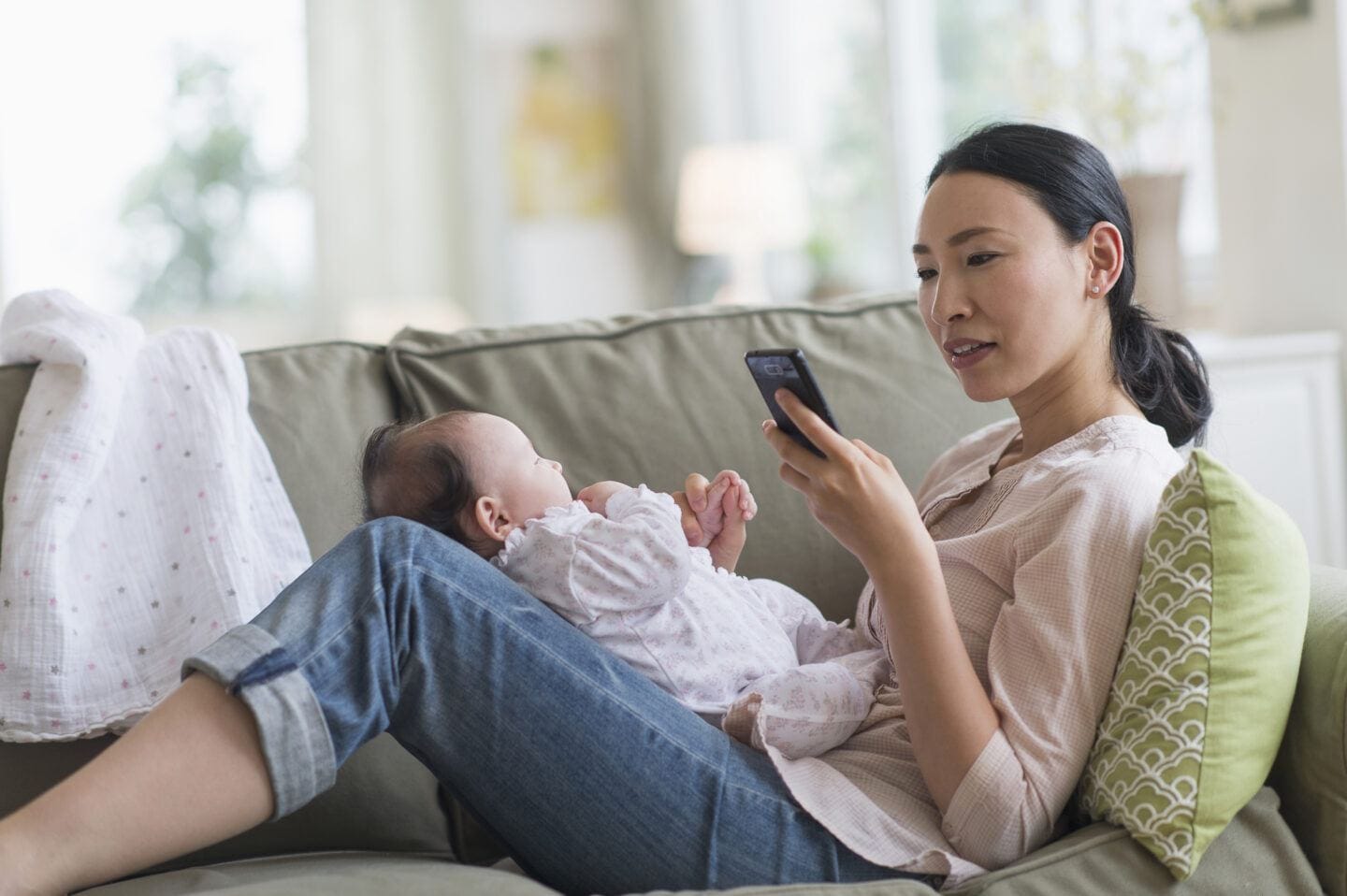 mom on her phone while holding a baby on her lap - baby feeding apps