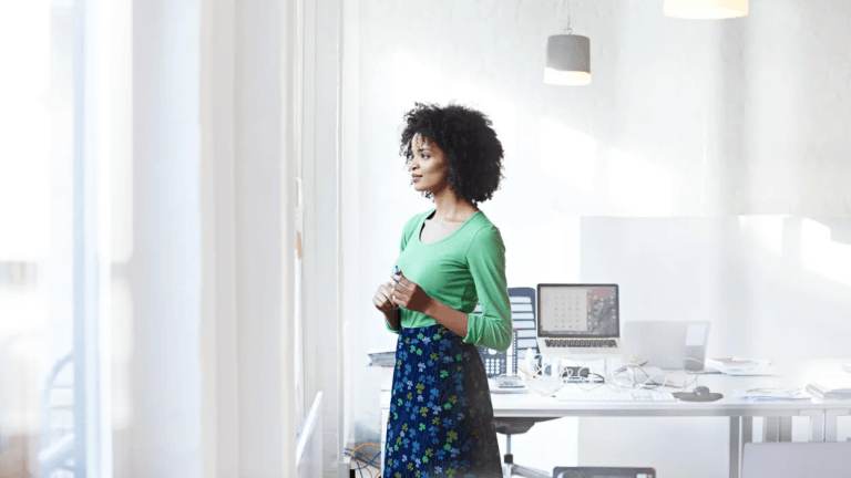 woman-in-business-office-staring-out-window- when to tell your boss you're pregnant