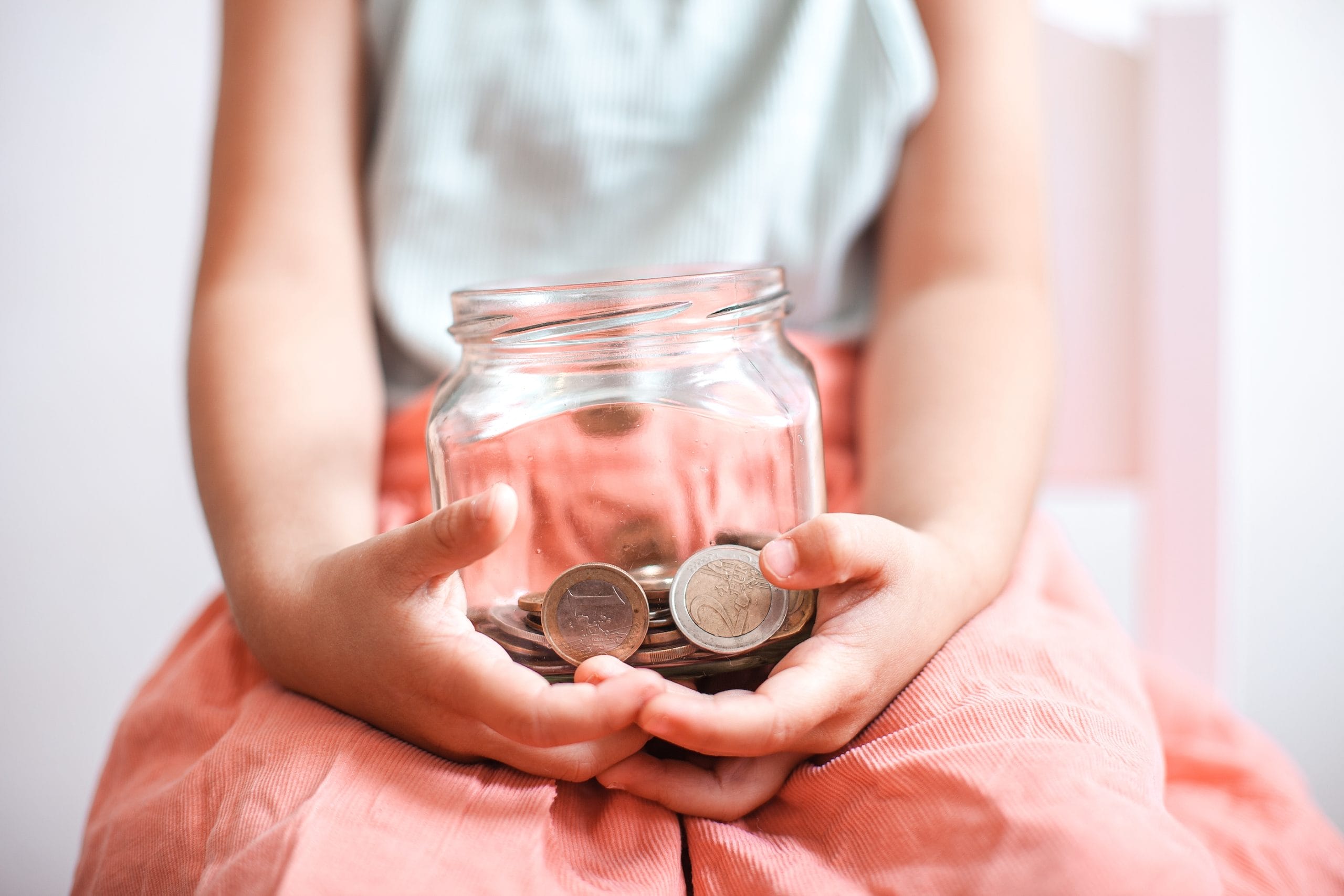 girl holding money jar- better money habits