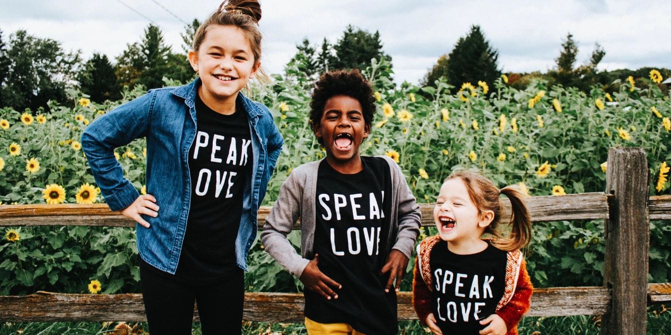 kids standing in front of a sunflower field making silly faces - how to raise kind kids