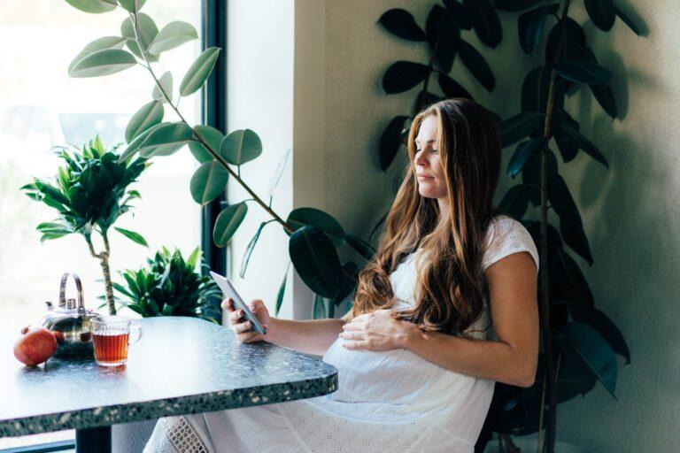 pregnant woman sitting in kitchen looking at phone