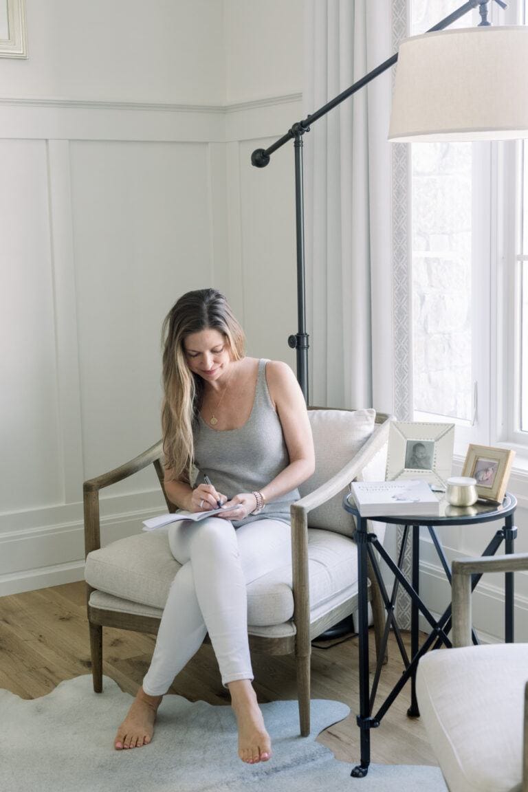 woman sitting on couch writing in journal- New Year's Intentions