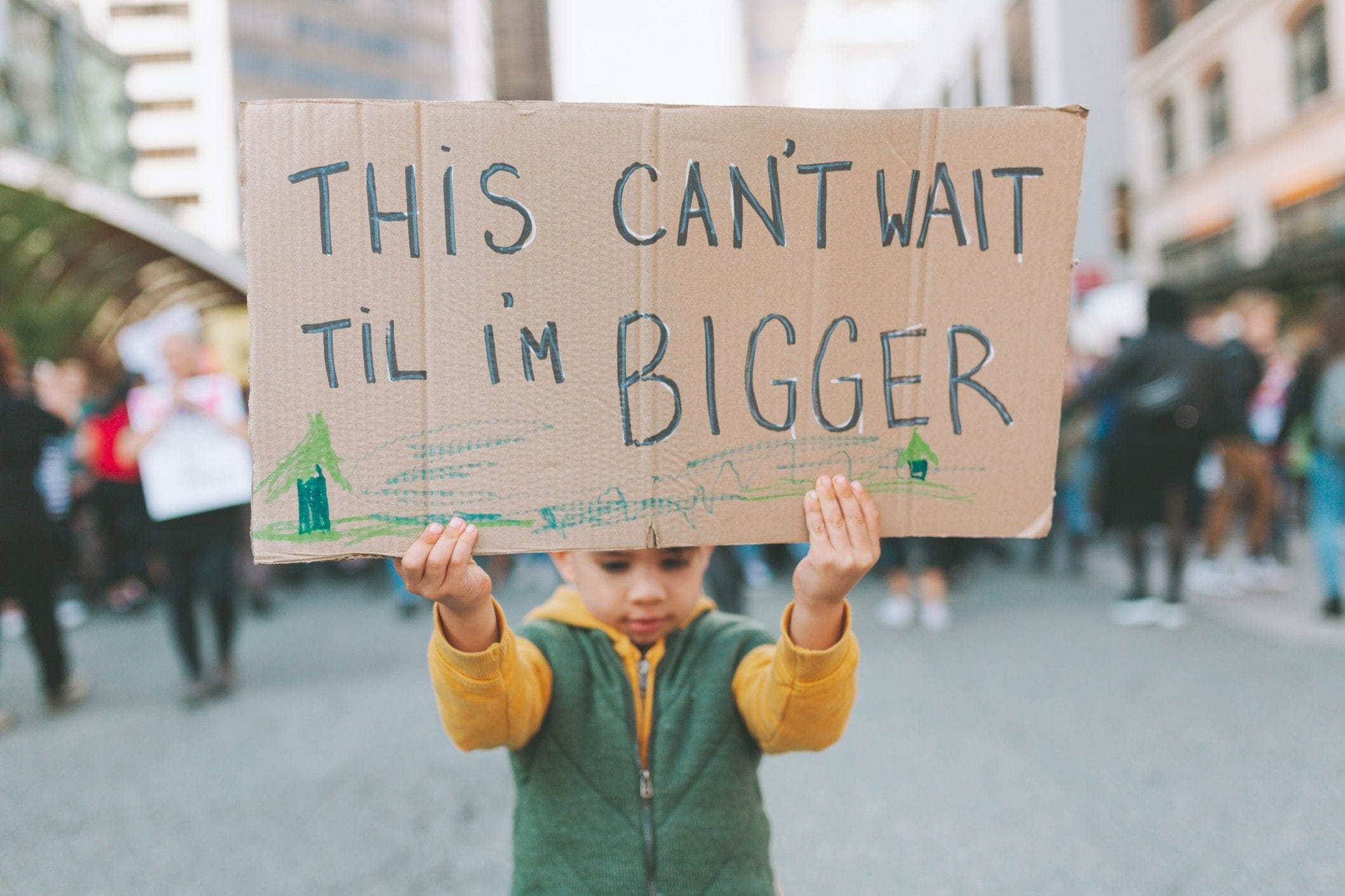 how to talk to kids about climate change - child holding a sign for earth day