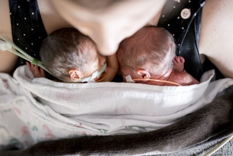 mom holding prematurely born twins, learning how to care for nicu baby