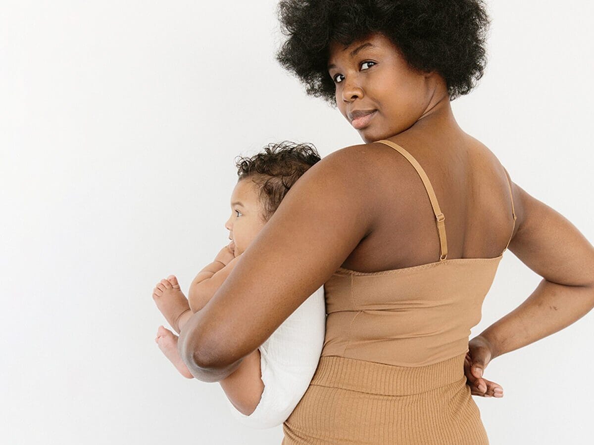 mom holding a newborn looking over her shoulder - best nursing tanks